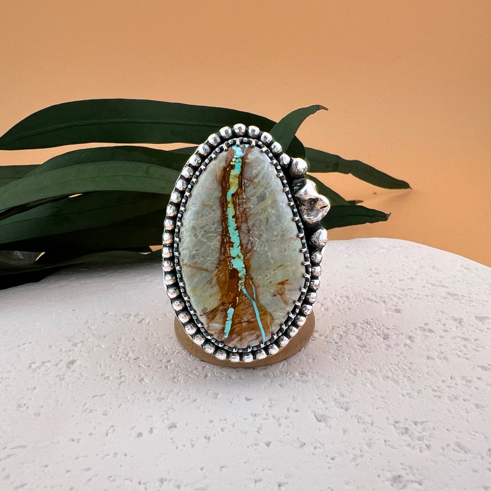One of a kind Royston ribbon turquoise ring set in sterling silver with hand-made silver nugget accents, displayed on a white stone surface.
