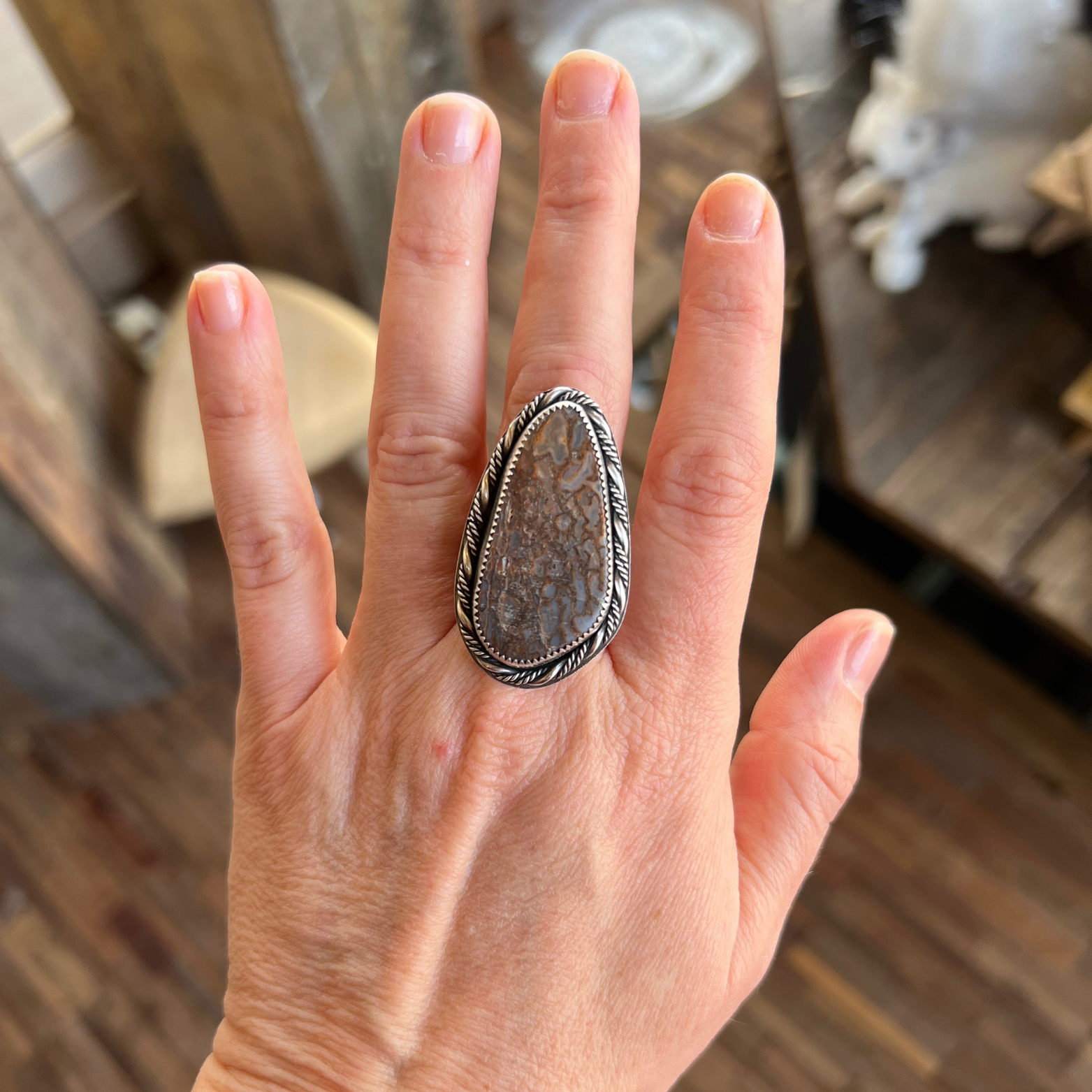 Fossilized dinosaur bone ring set in sterling silver worn on hand, showing natural cellular pattern and earthy tones.