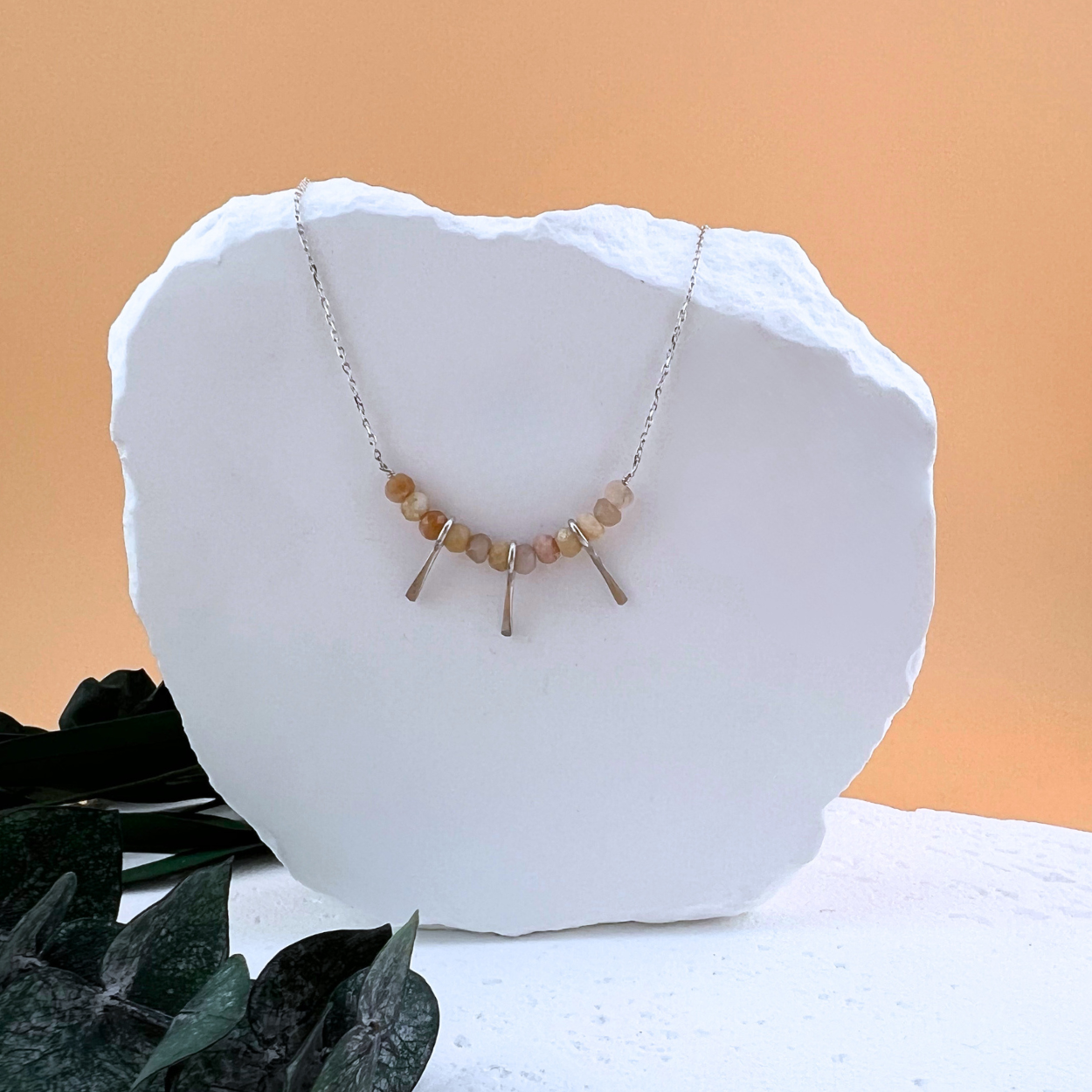 Delicate sterling silver Fringe + Fire Necklace with faceted Mexican fire opal beads and tiny hand-hammered silver fringe, displayed on a white stone backdrop.