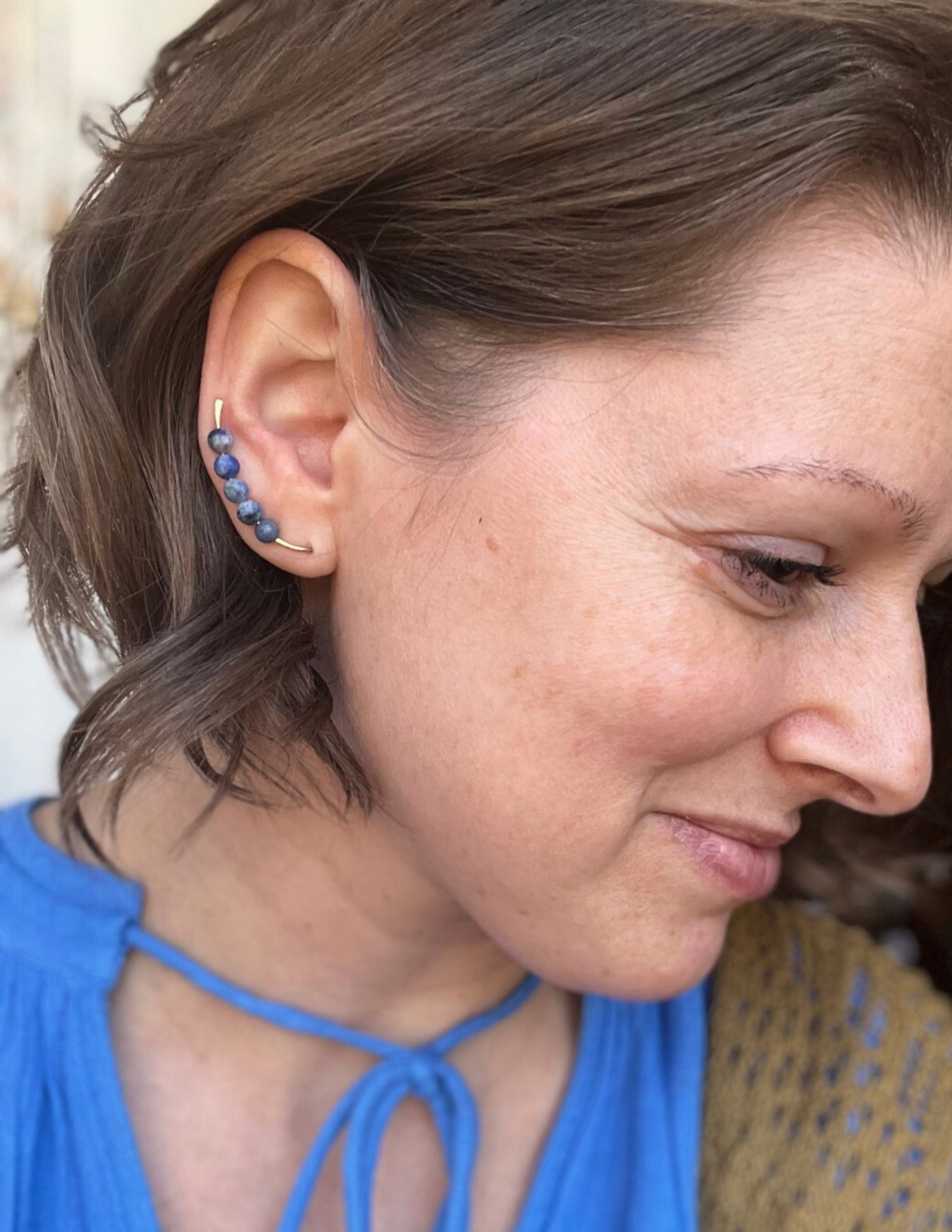 woman wearing a beaded ear climber style earring.