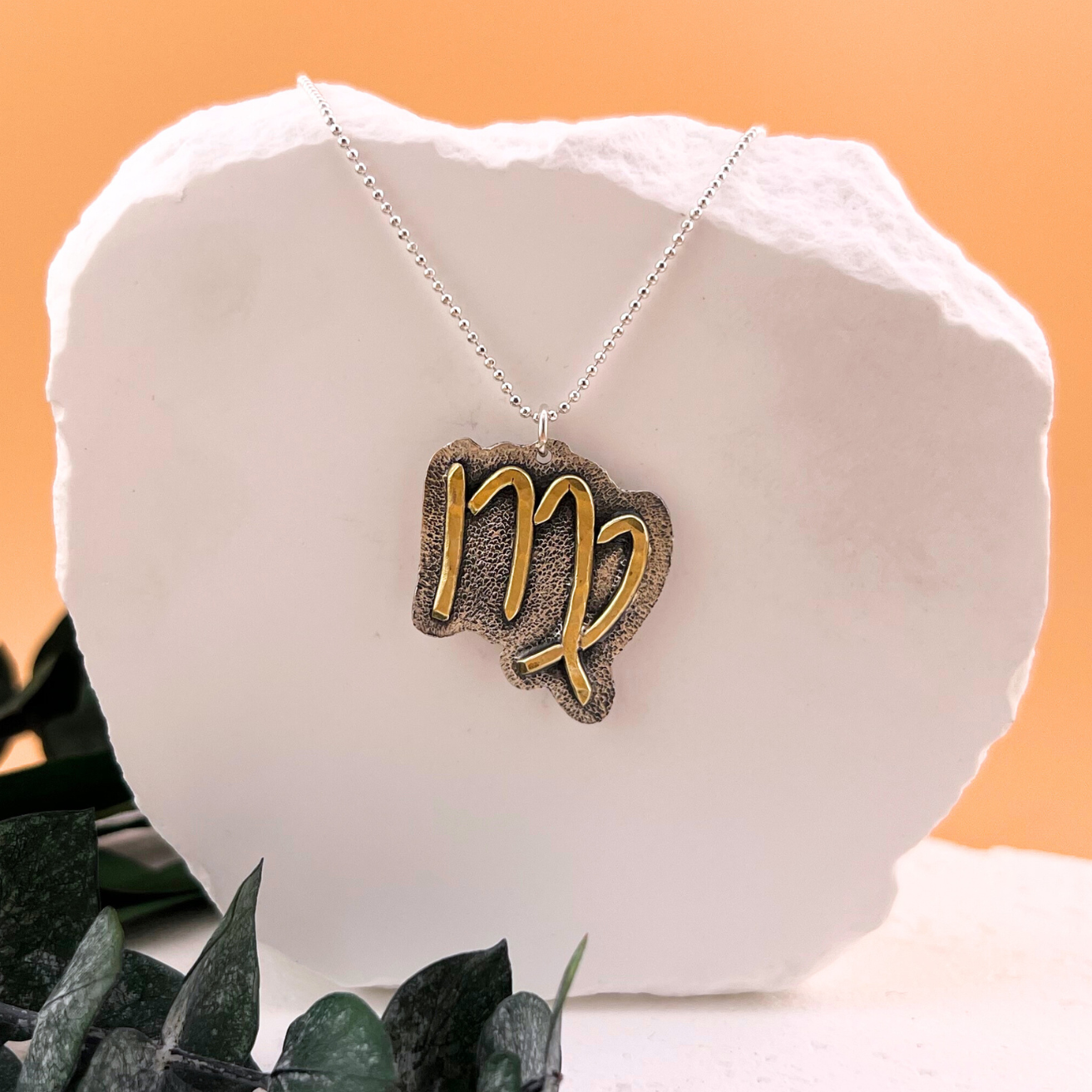 Virgo zodiac necklace with brass symbol on textured sterling silver back plate.