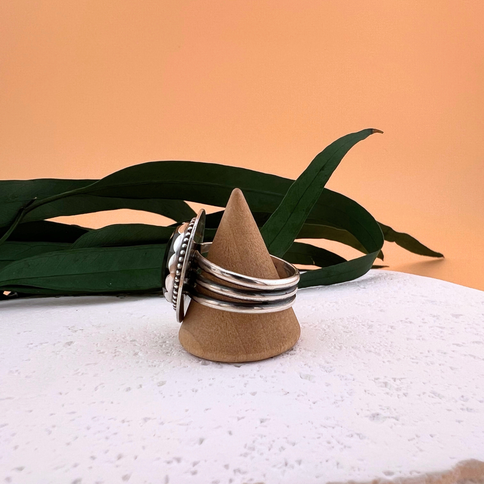 Side profile of a velvet obsidian ring in sterling silver on a wooden ring stand, showing the handcrafted bezel and setting detail.