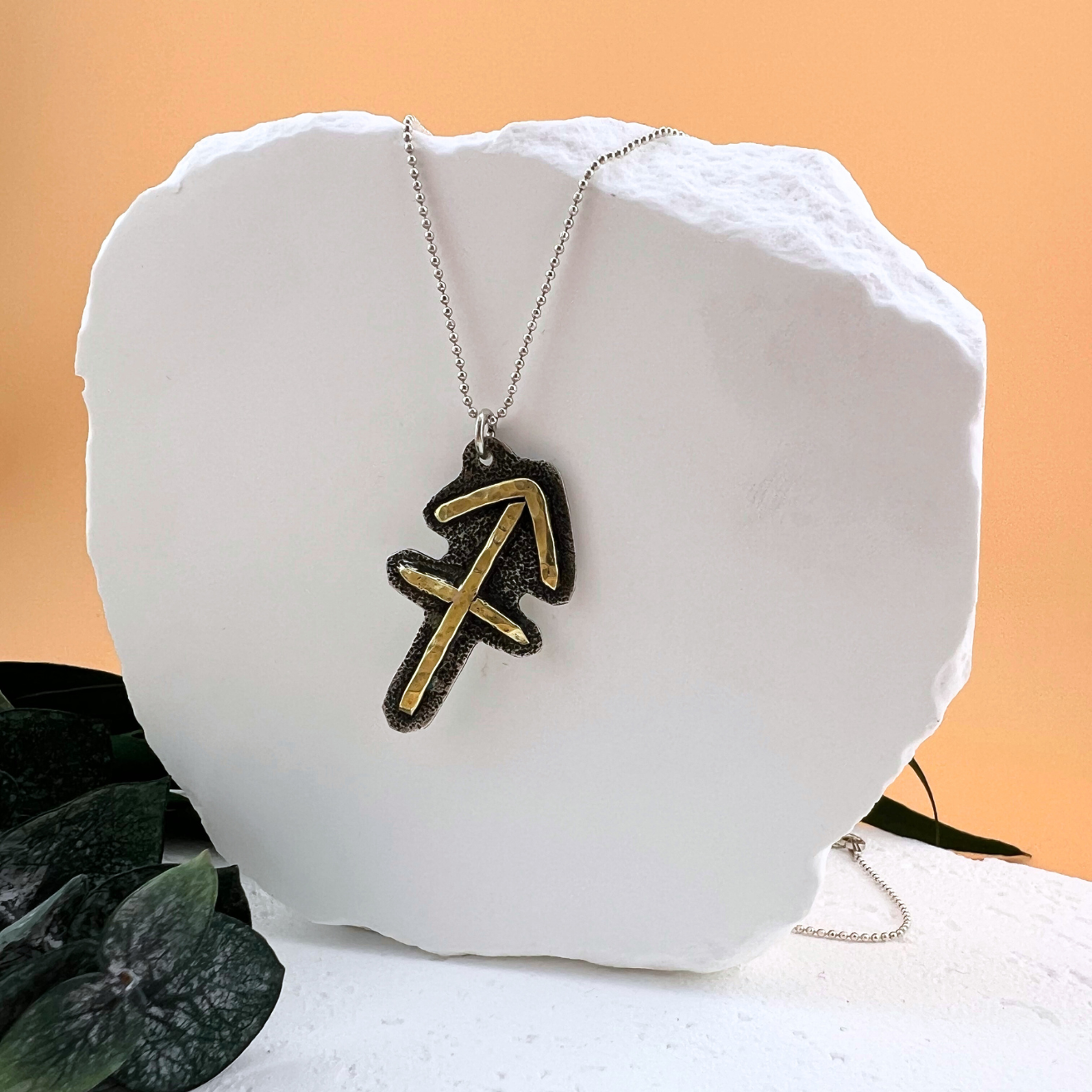 Sagittarius zodiac necklace featuring brass arrow symbol on sterling silver.