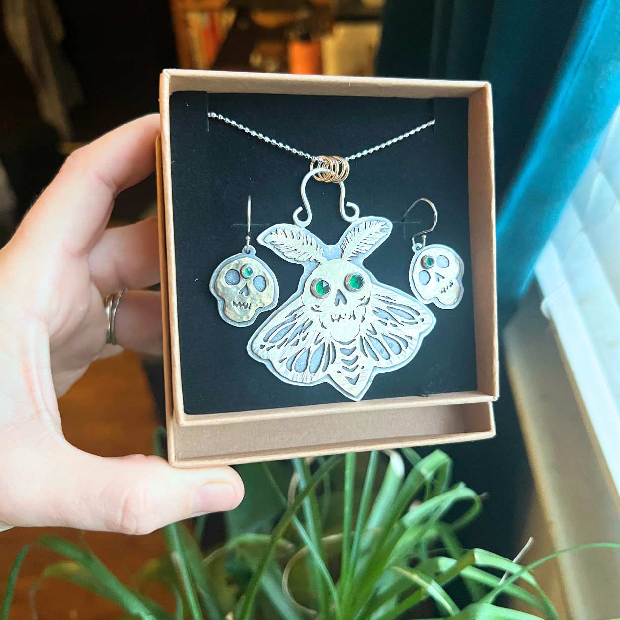 Custome death moth and skull earring and necklace set, saw pierced brass on sterling silver with faceted emerald gemstone accents.