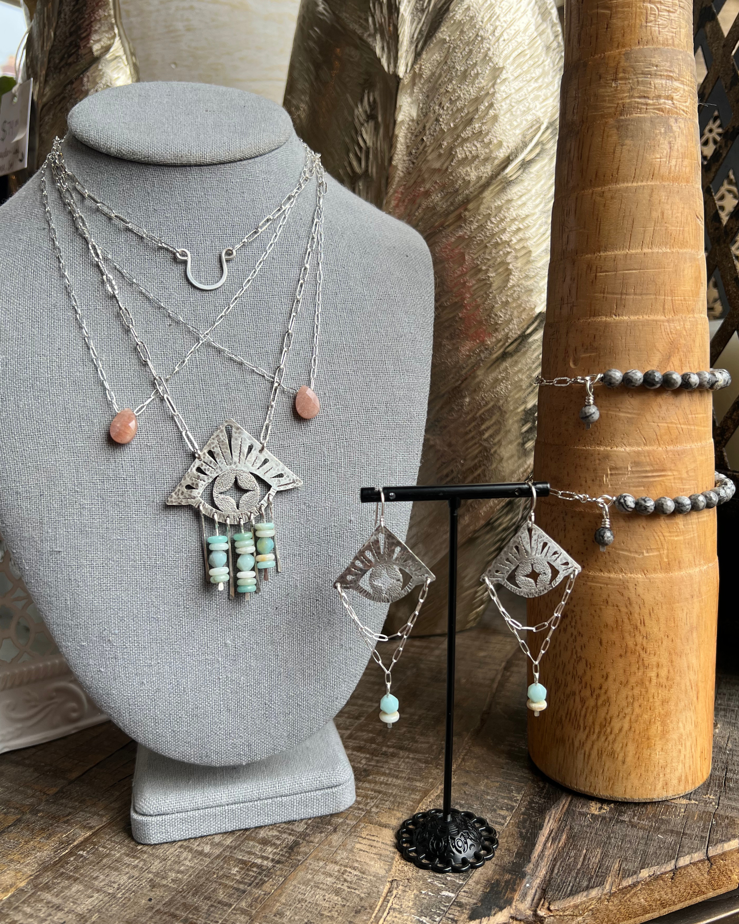 Evil eye Necklace and earrings displayed with beaded bracelets, a peach moonstone necklace, and a simple silver accent necklace.