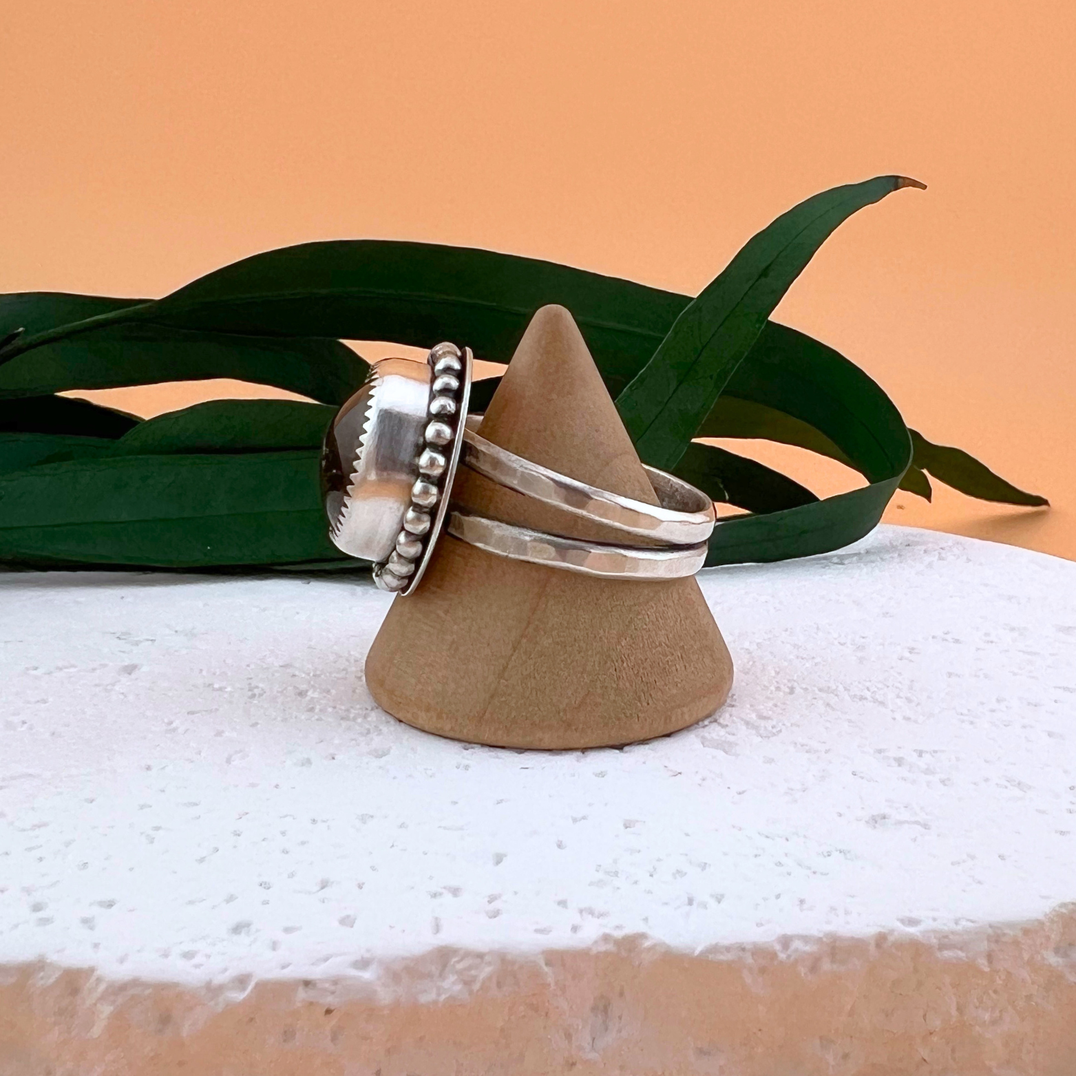 Side profile of a Garden Quartz ring in sterling silver on a wooden ring stand, showing the handcrafted setting and depth of the stone.