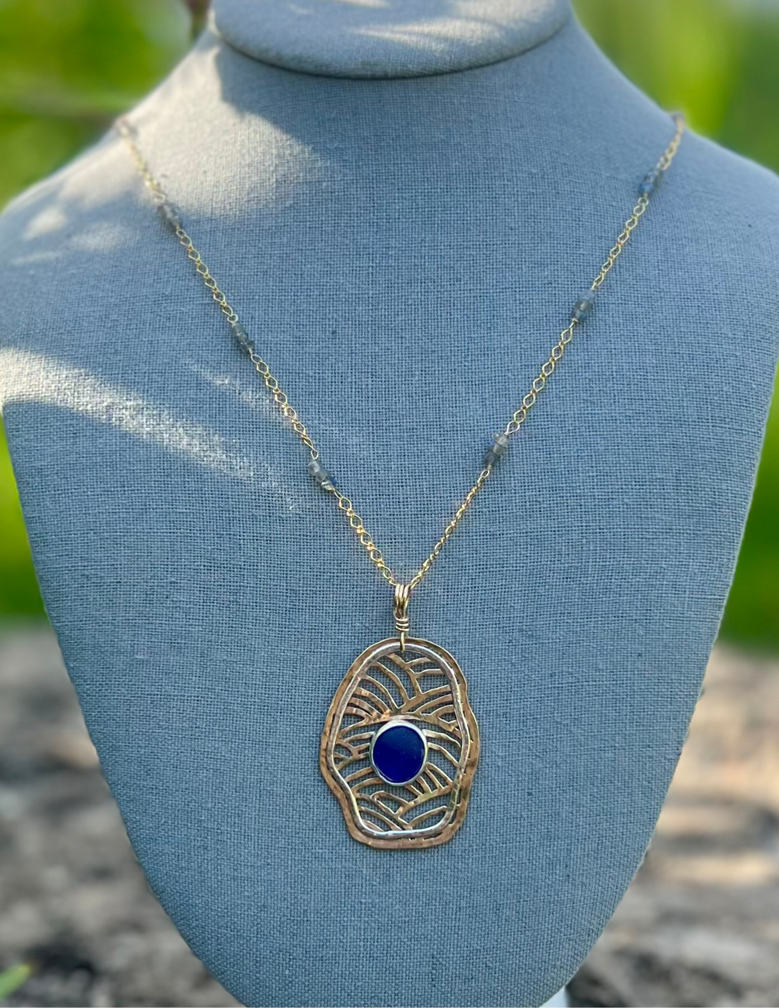 Saw priced brass Free Flow necklace with sterling accents and a cobolt blue cabochon set in the center.