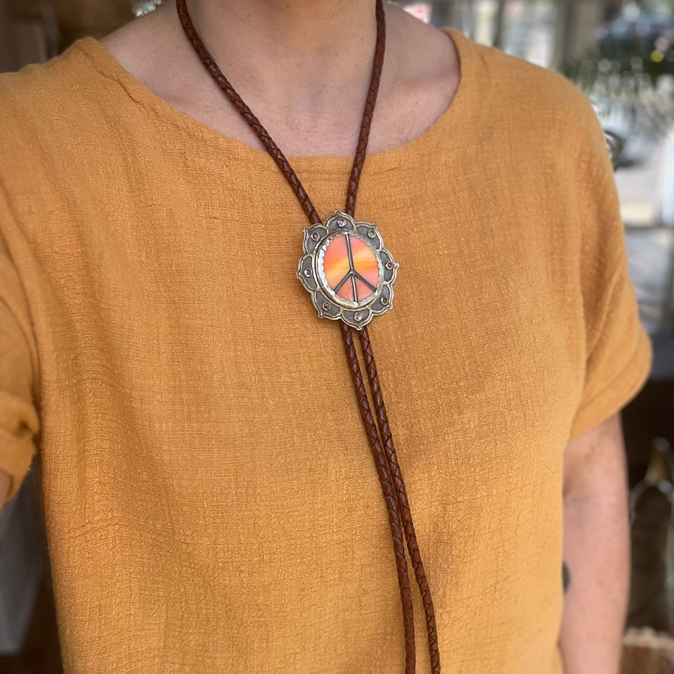 Citrus-colored stained glass Peace Portal bolo tie accented with tourmaline, shown worn as a bold, colorful accessory.