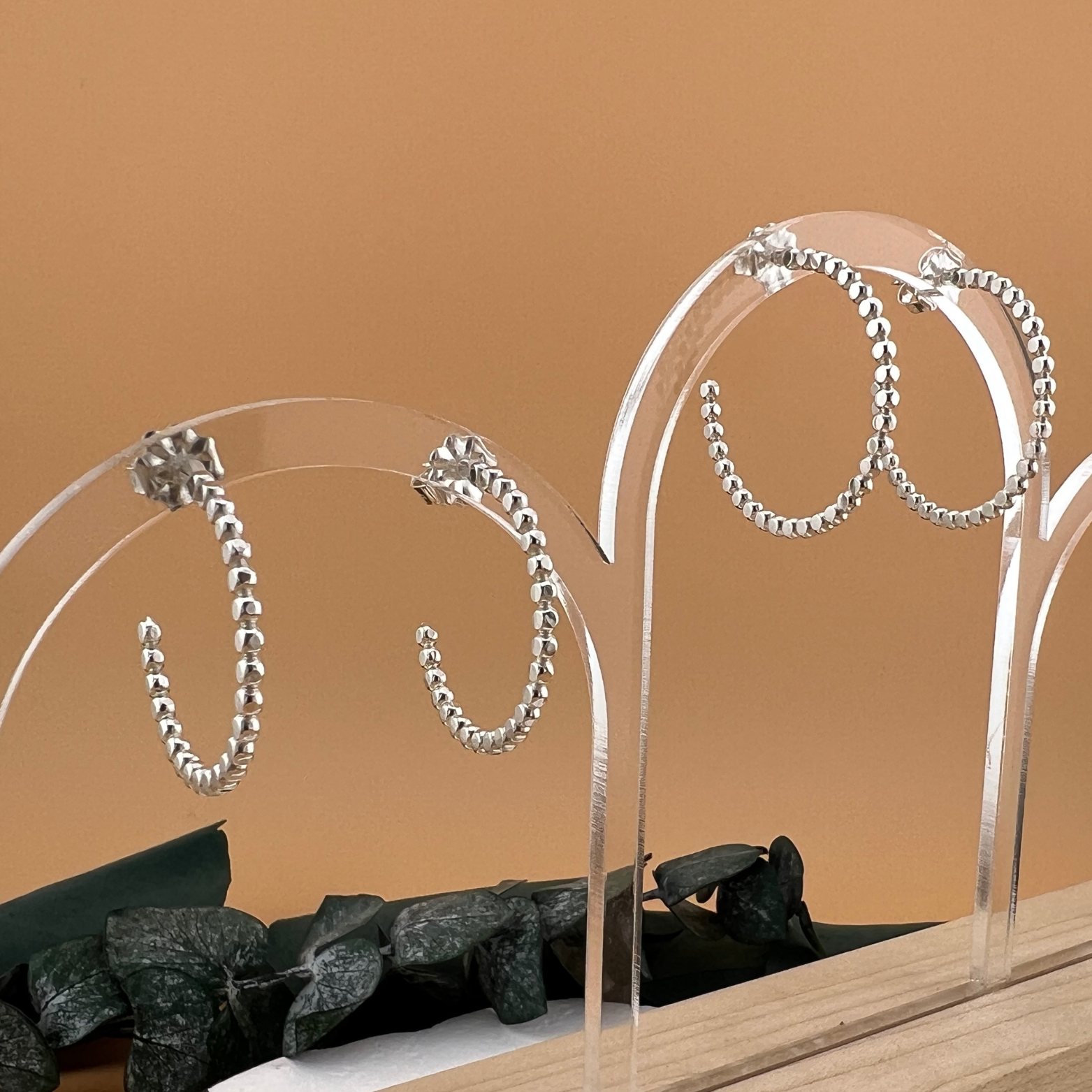 Side view of sterling silver post hoop earrings made from beaded wire, lightly hammered to reflect light, shown in small and large sizes.