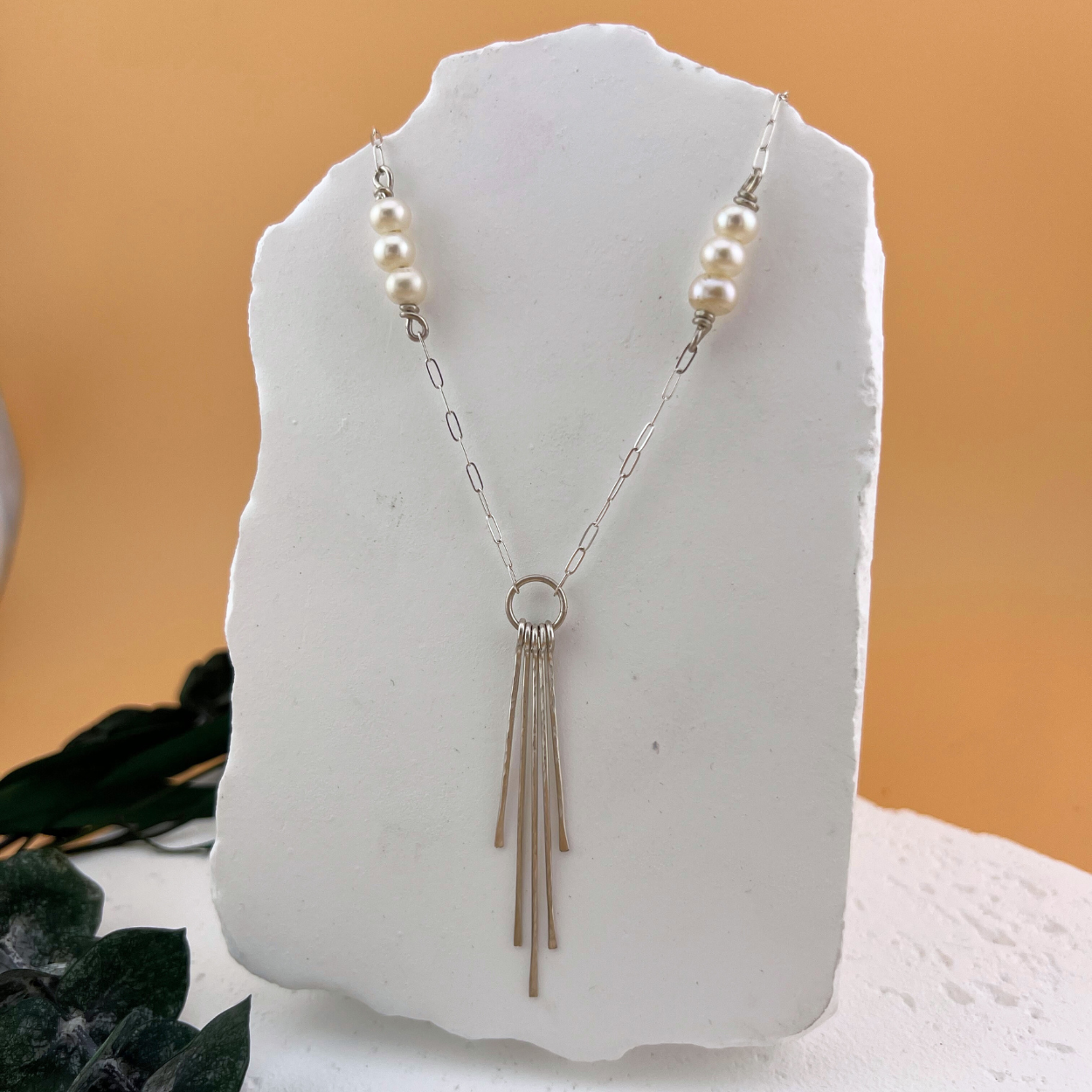 Lumen Fringe Necklace in sterling silver with AAA freshwater pearls and a cascading silver fringe pendant on a neutral backdrop.