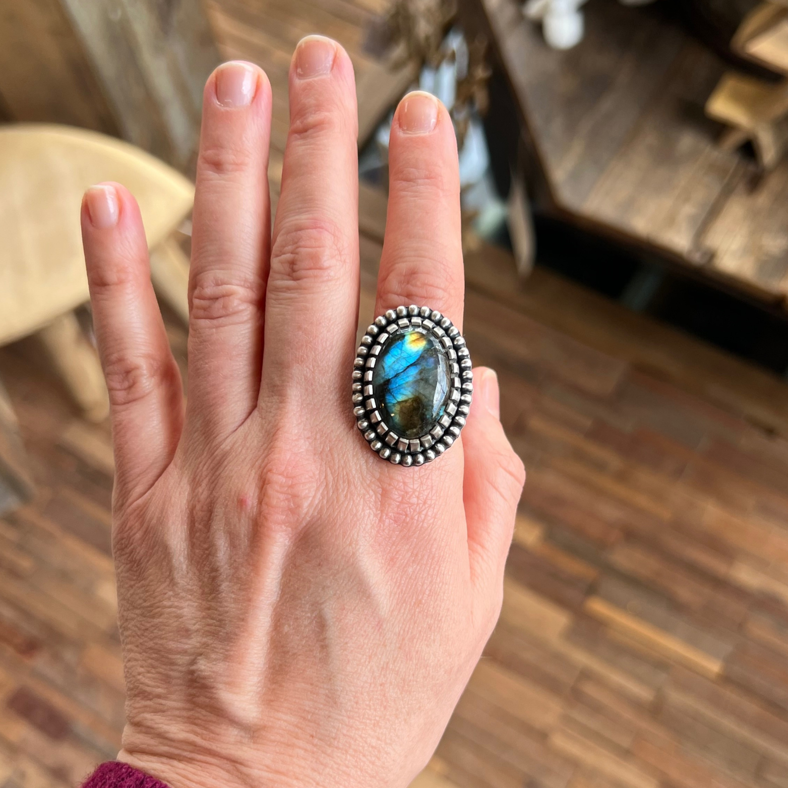 Labradorite ring set in sterling silver worn on hand, showing vivid blue and green flash in natural light.