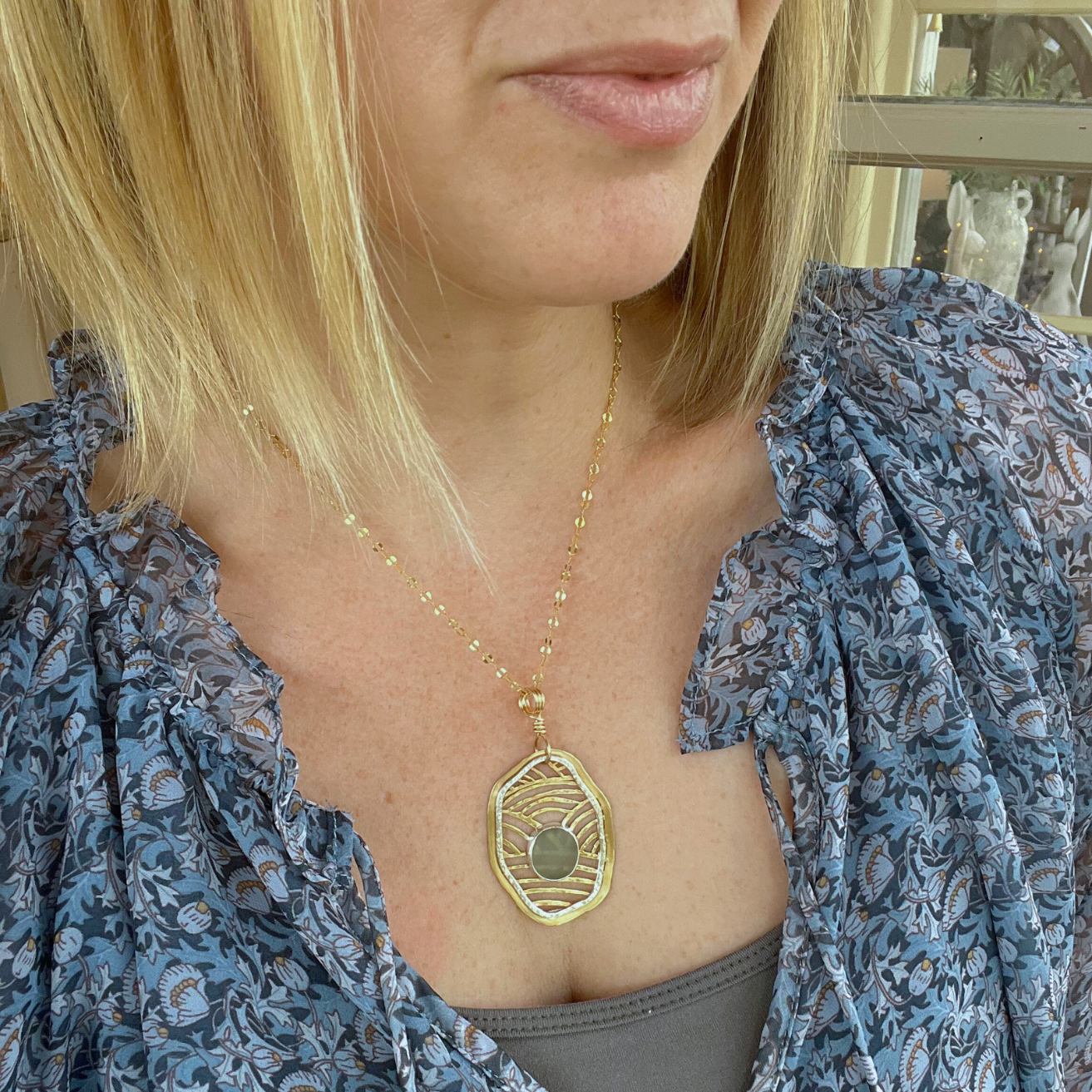 Sea glass necklace with saw pierced sterling silver and gold fill bezel on model.