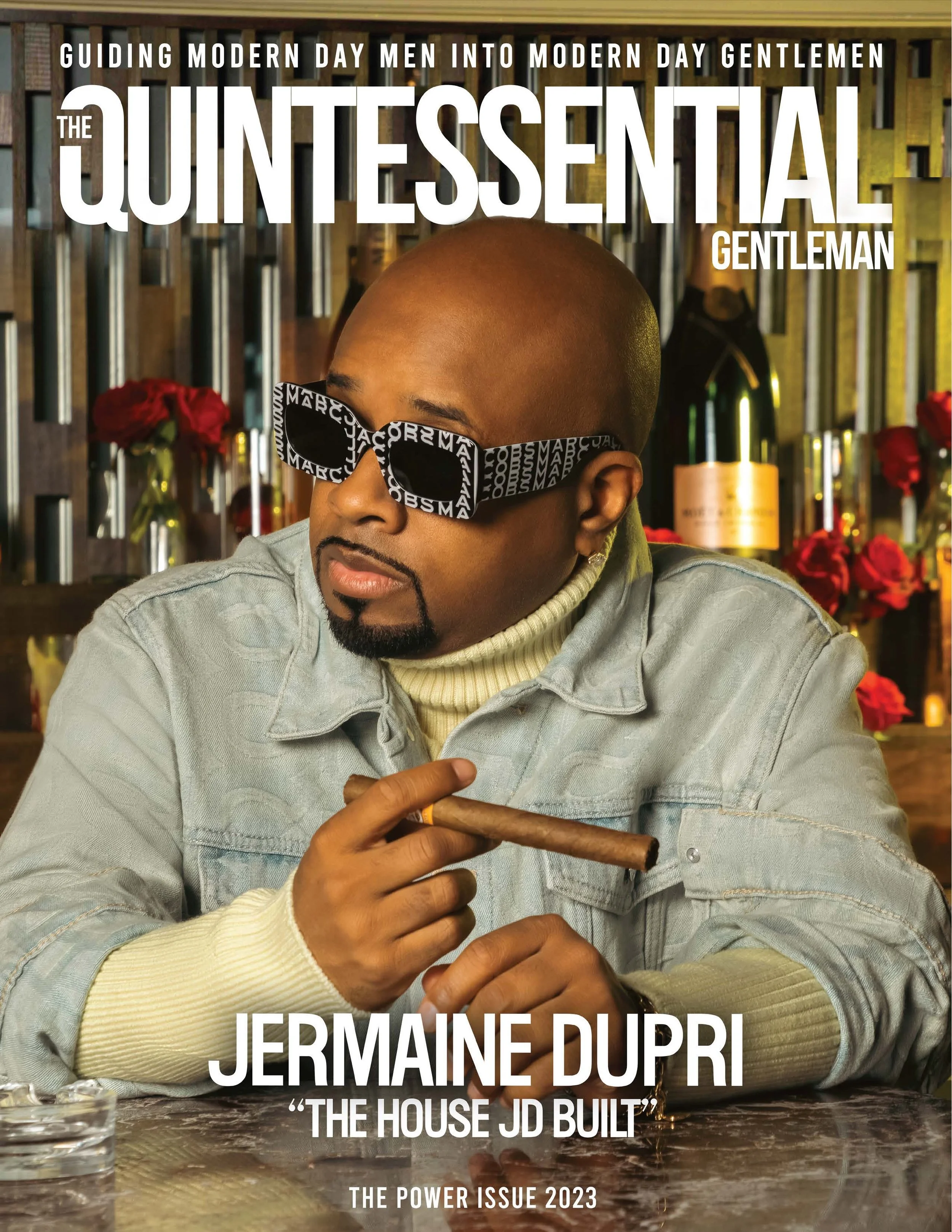 Magazine cover featuring Jermaine Dupri wearing large black sunglasses with white text, holding a cigar, in a stylish setting with red roses and champagne in the background.