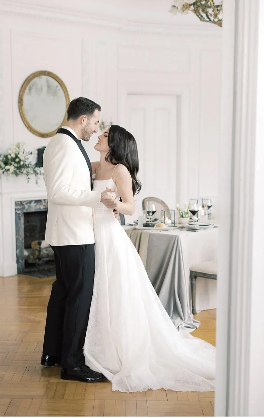 A bride and groom dancing during their wedding reception in an elegant, decorated room.