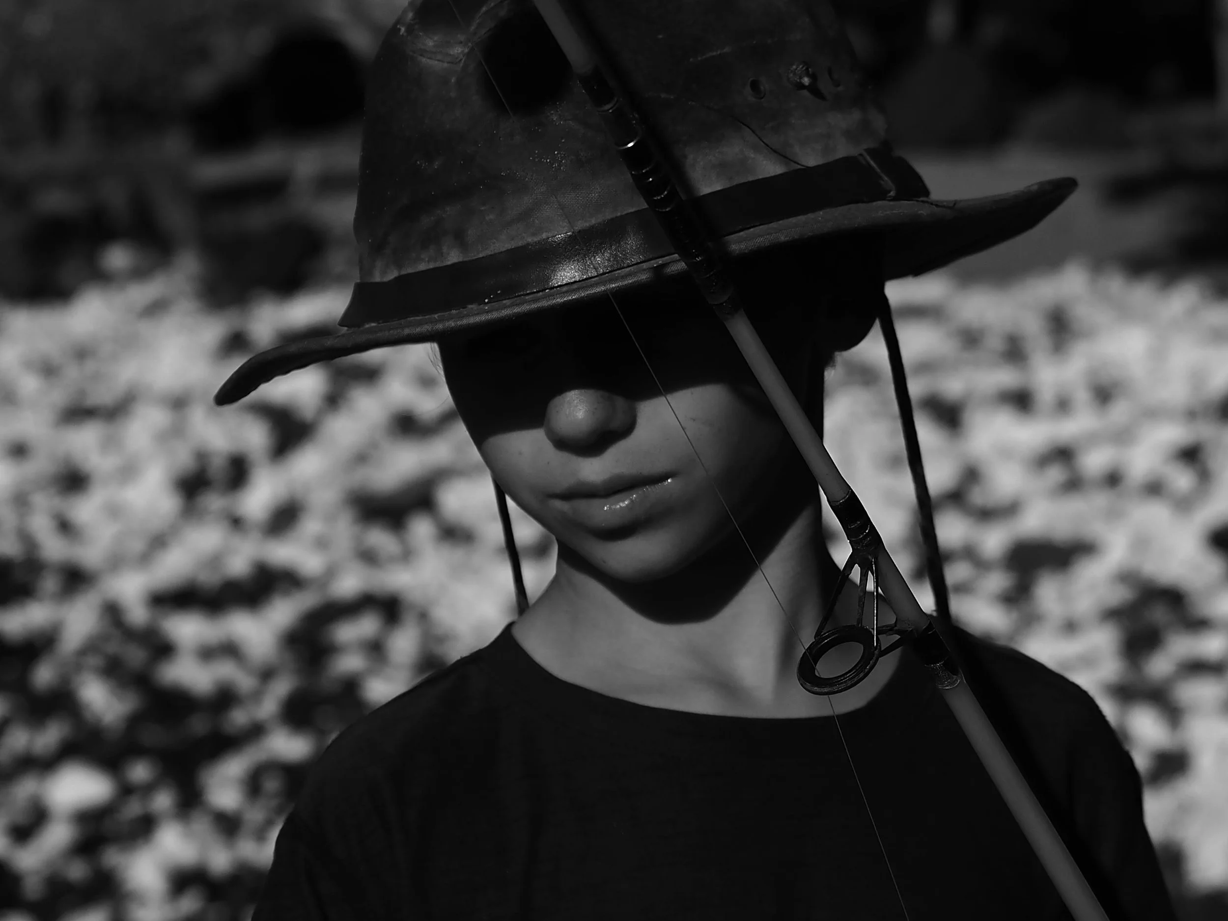 Boy wearing hat and fishing black and white