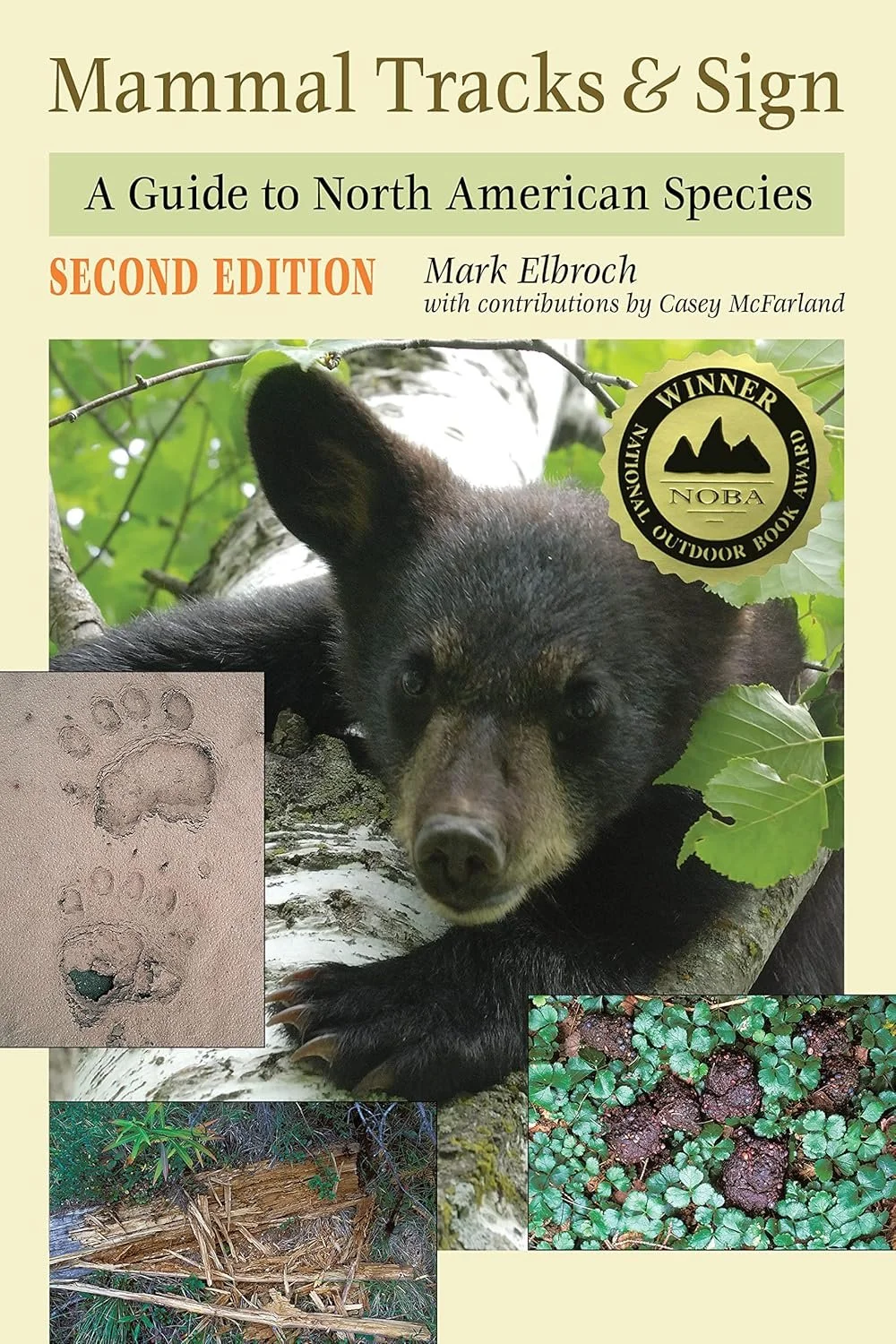 Cover of a book titled "Mammal Tracks & Sign: A Guide to North American Species" by Mark Elbroch, second edition, with a sticker indicating it is an award winner from the National Outdoor Book Awards. The cover features a black bear resting on a tree trunk with green leaves, paw prints in dirt, a nest, and ground cover with plants.