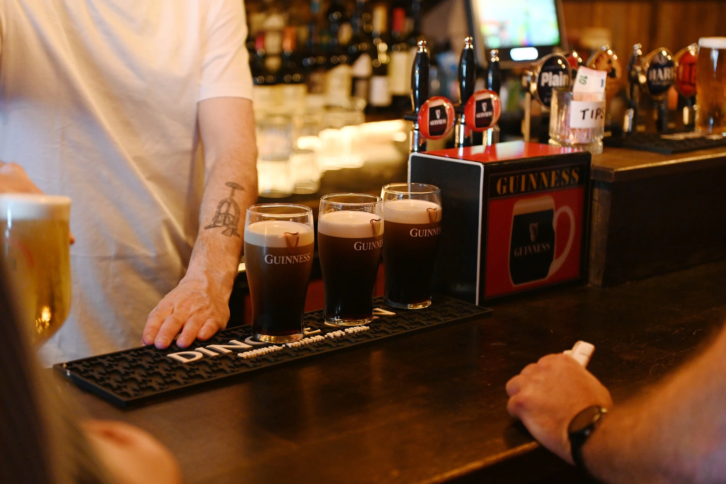 Three glasses of Guinness stout beer on a bar counter.