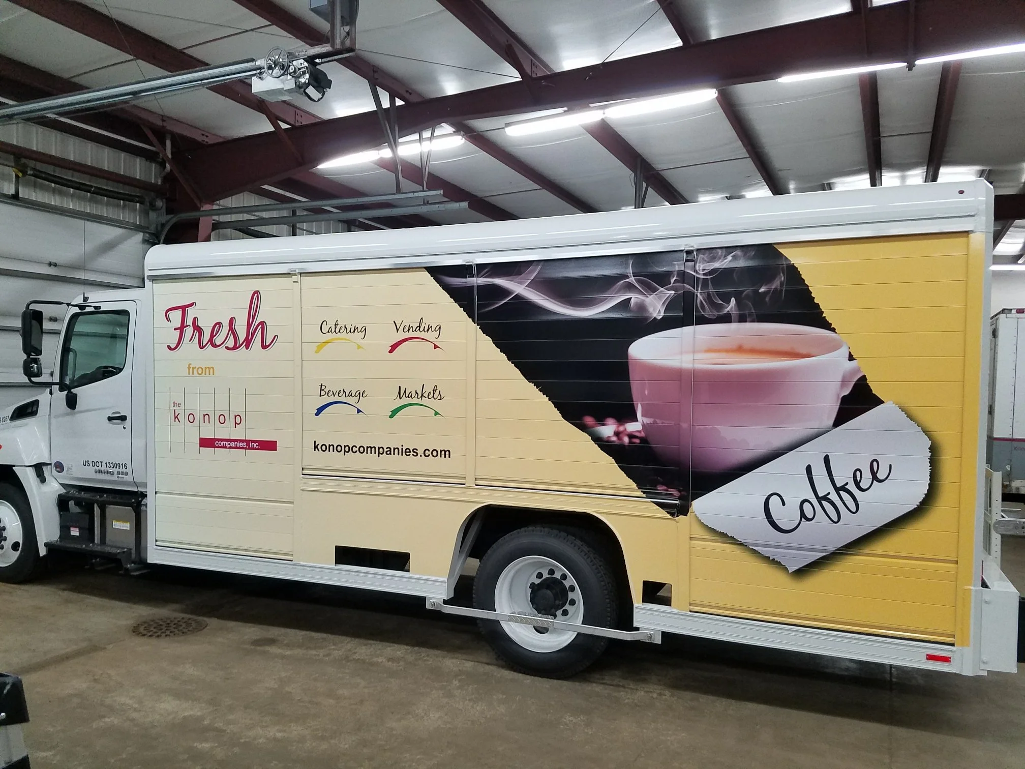 A food truck with a large graphic of a steaming coffee cup and the word 'Coffee' on the side. The truck has text advertising fresh coffee from Konop Company, including catering, vending, beverage, and markets services.