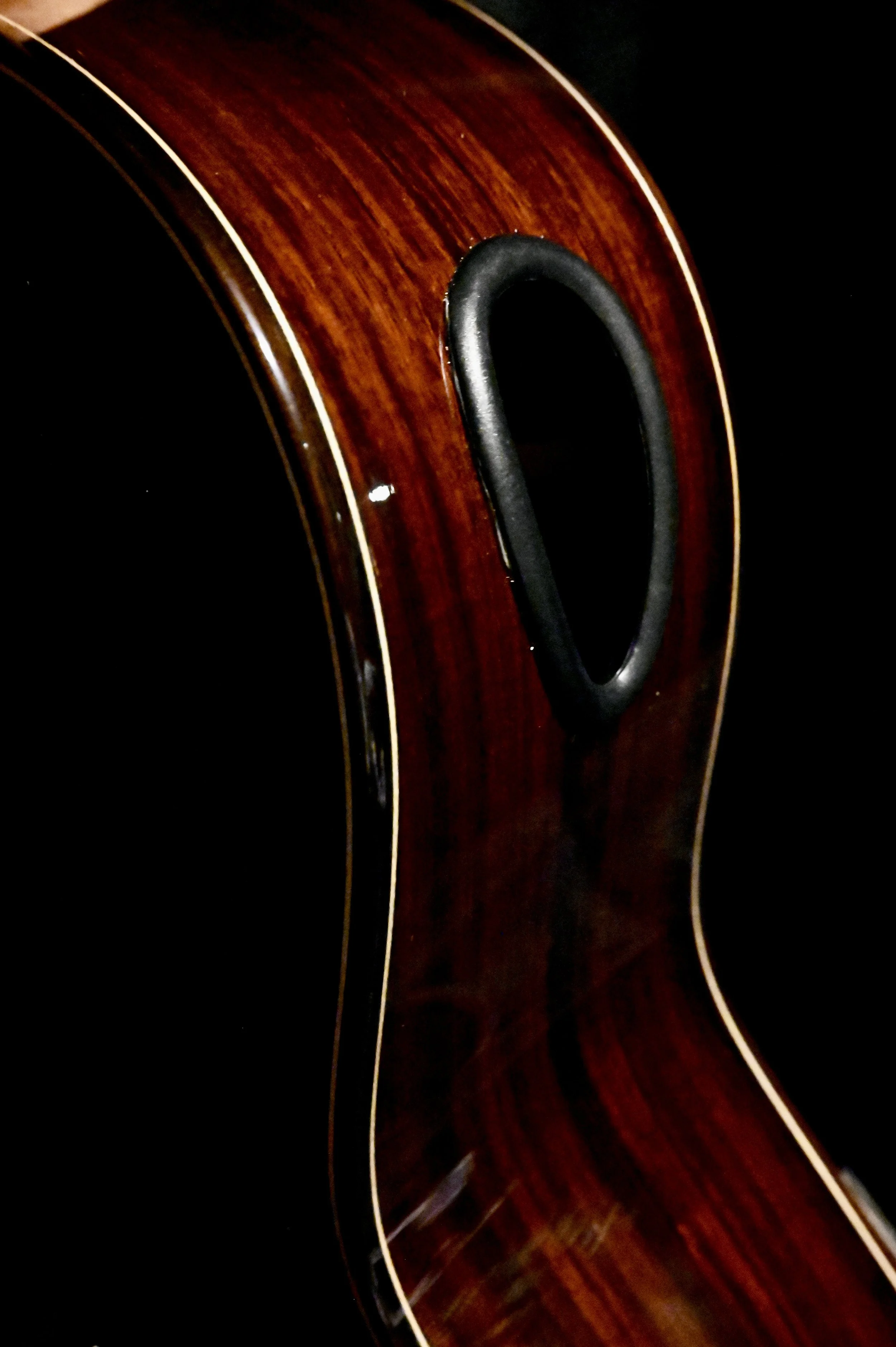 Close-up of a wooden acoustic guitar body with a black sound hole and binding.