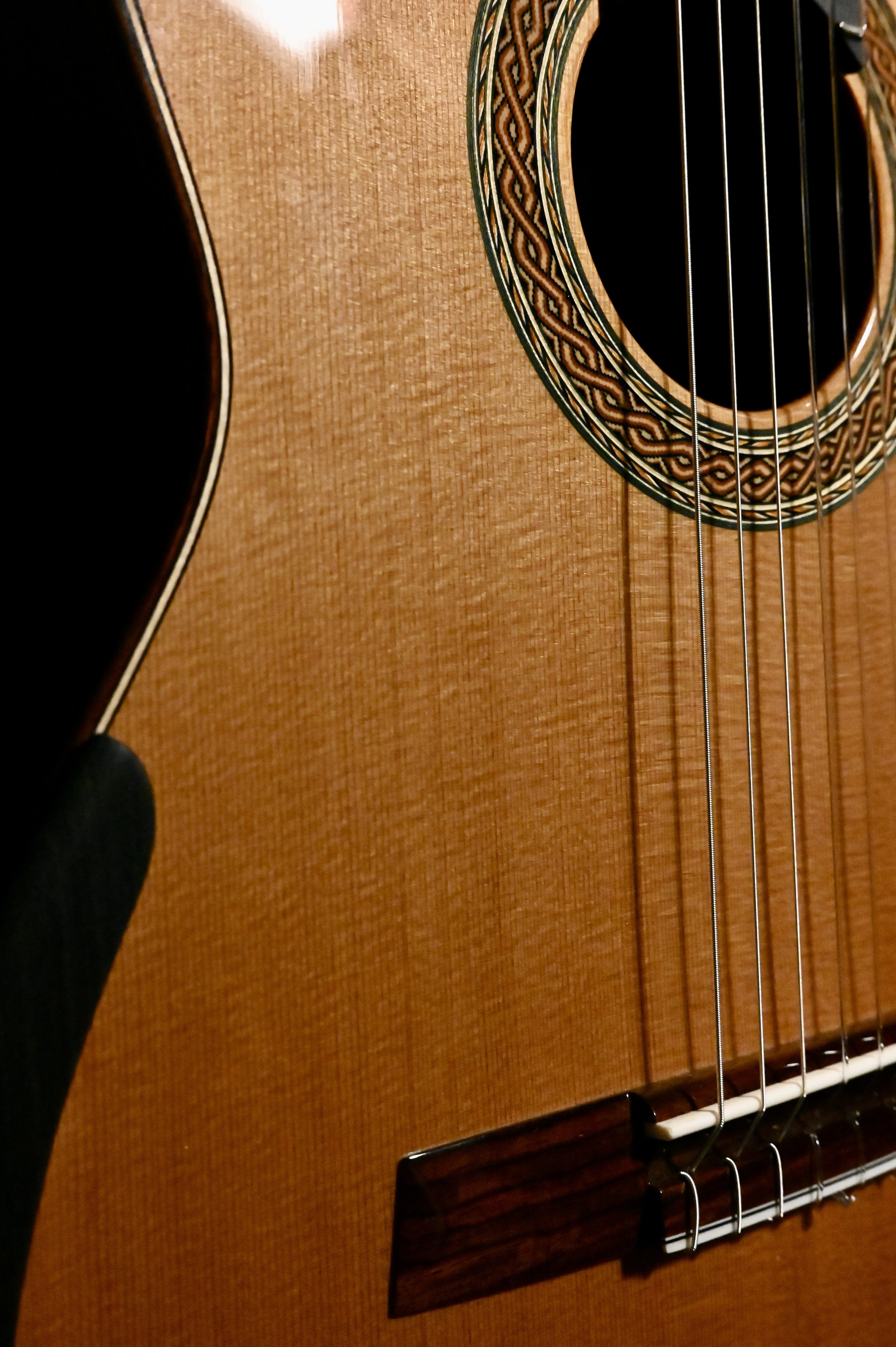 Close-up of an acoustic guitar showing sound hole, strings, and wooden body.