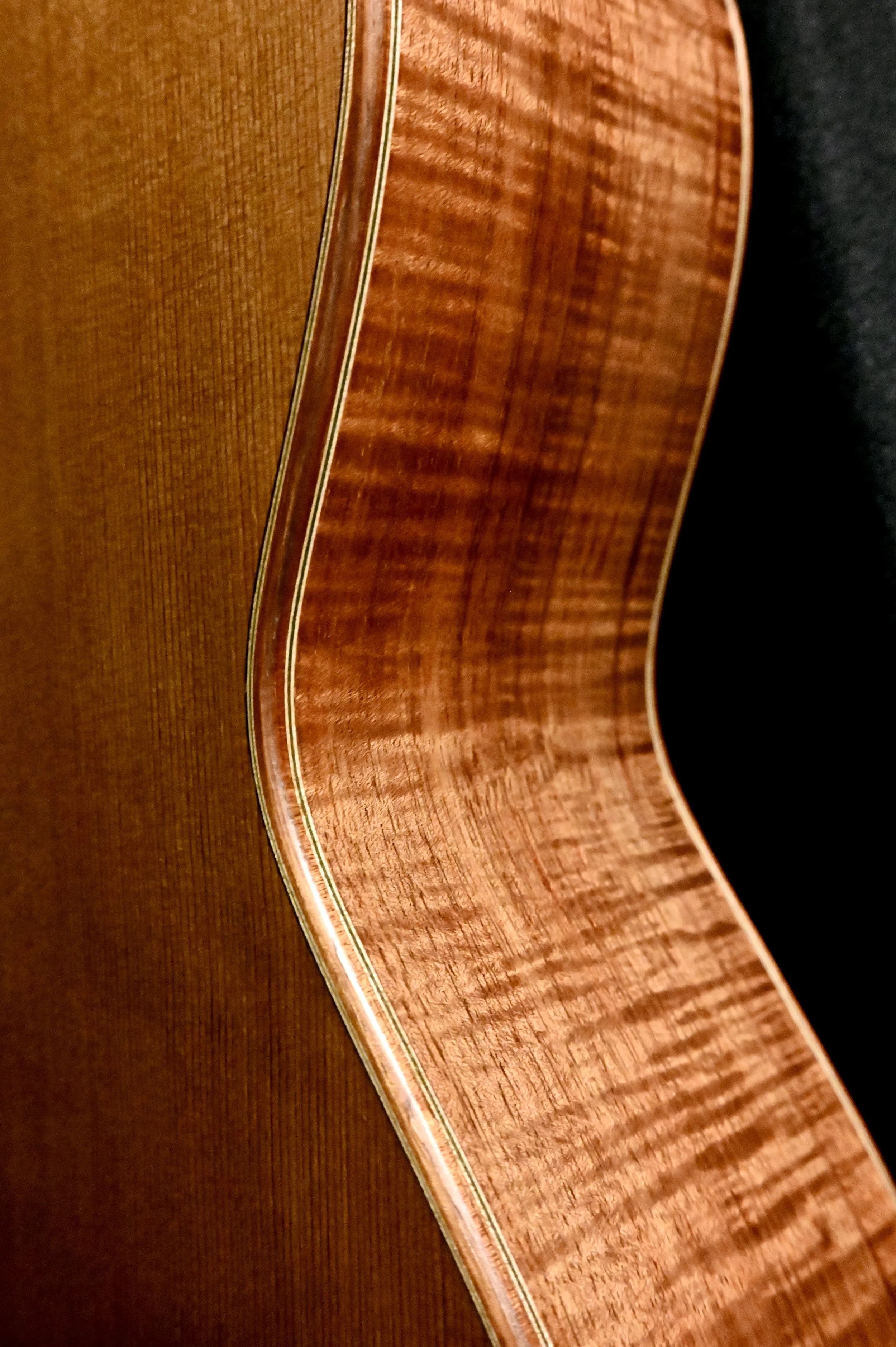 Close-up of the side of a wooden acoustic guitar.