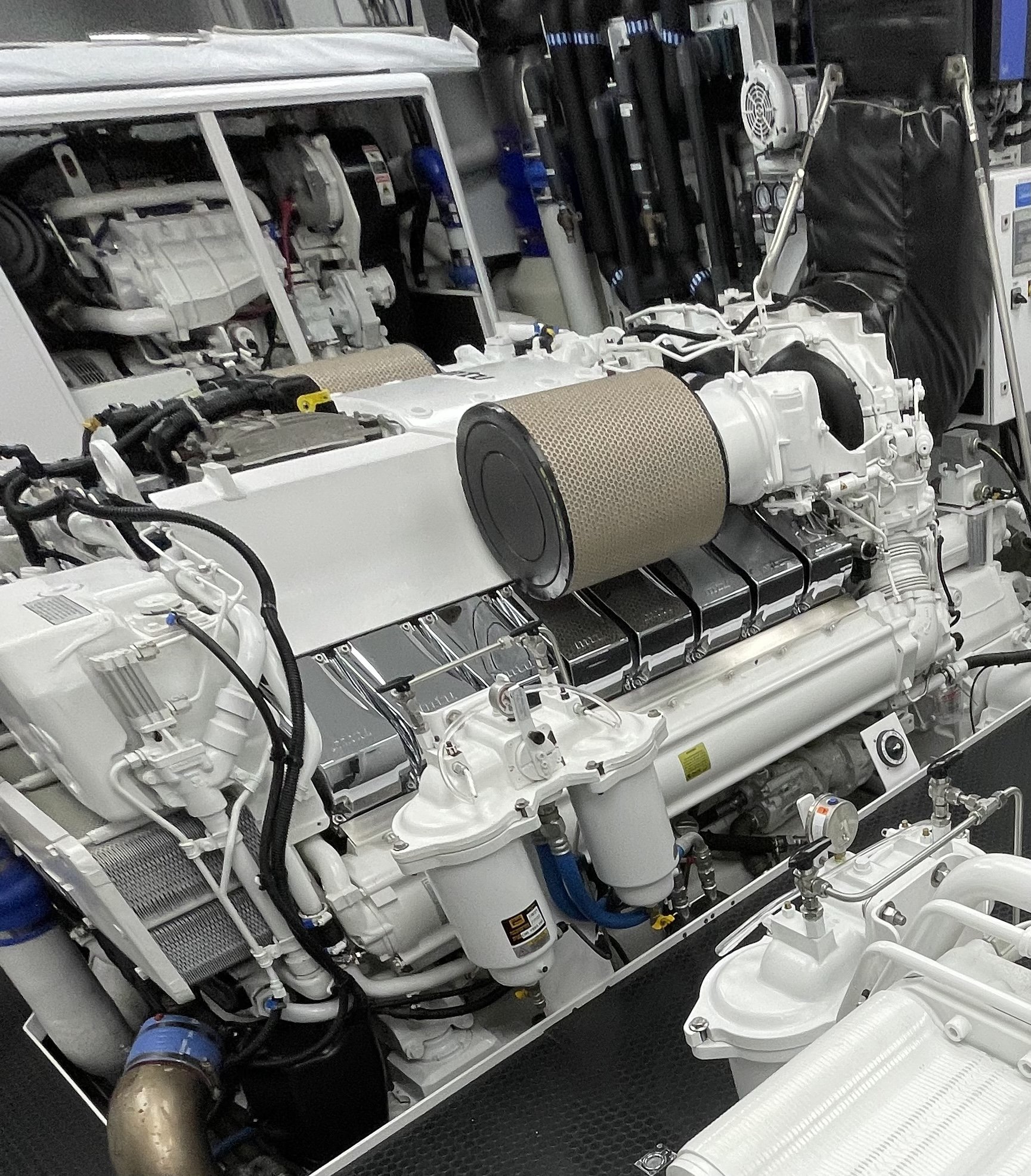 Close-up of a white marine diesel engine with visible filters, pipes, and mechanical components.