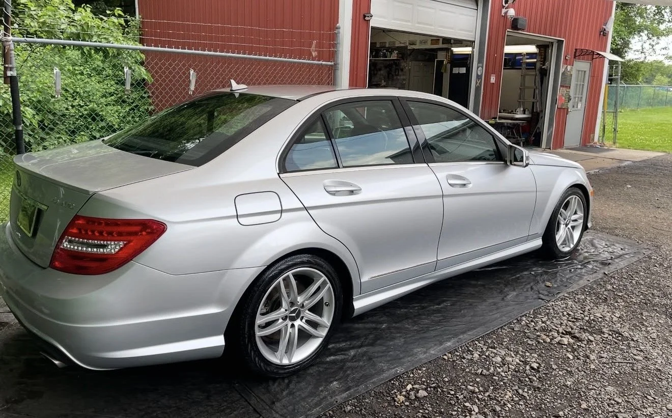A silver Mercedes-Benz sedan parked outside a red building with a garage.