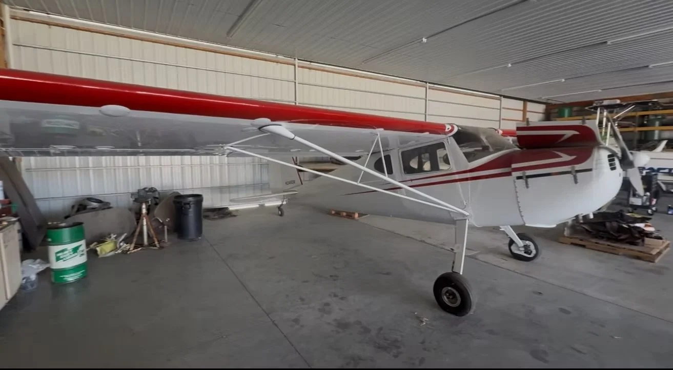 A small white and red propeller airplane inside a hangar.