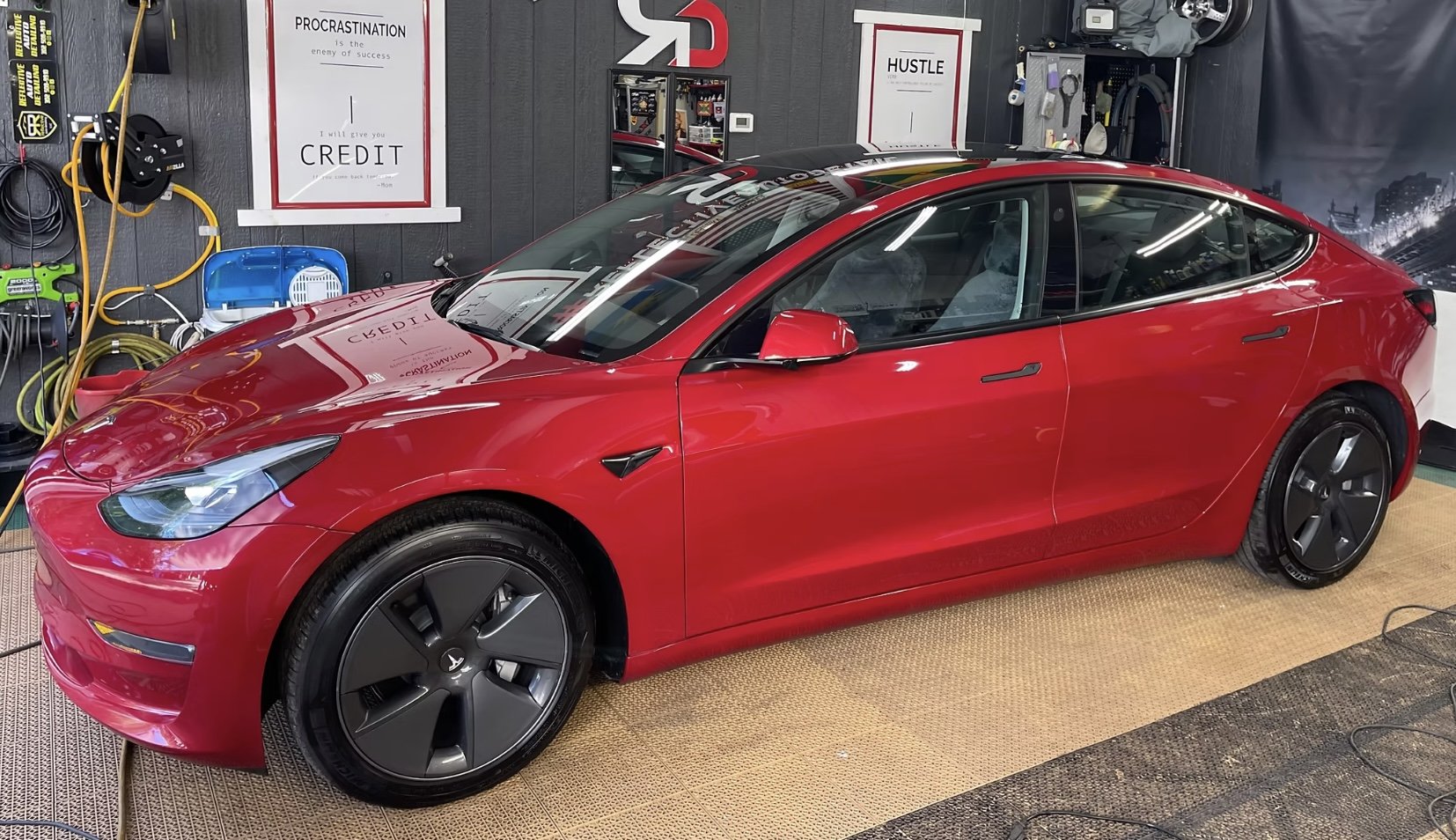A red Tesla Model S parked inside a garage or workshop.