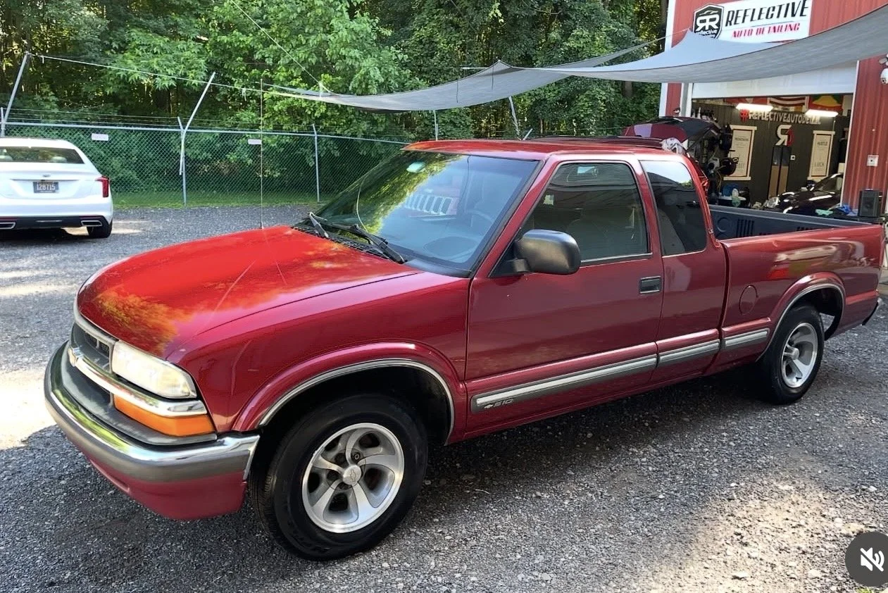 A red pickup truck parked outside a garage or auto service shop.
