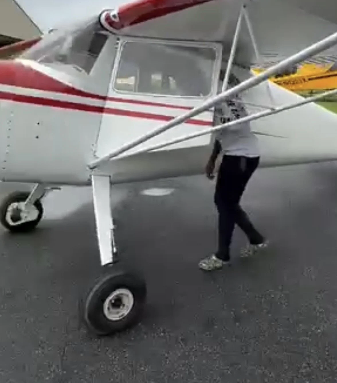 A person walking near small aircraft on tarmac.