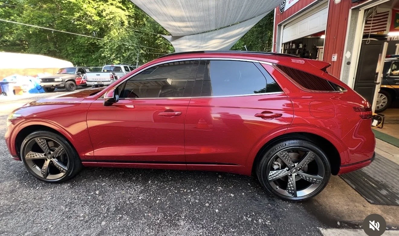 Red luxury SUV parked outside a garage with other cars visible in the background.