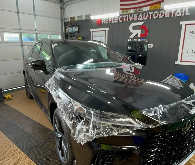 PPF FILM on front end and plastic wrap on the driver side front fender, inside a garage or auto detailing shop.