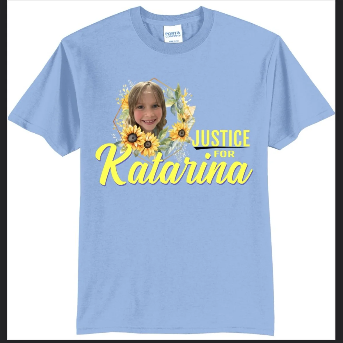 Light blue T-shirt with a print of a girl’s face surrounded by sunflowers, and text that reads 'Justice for Katarina' in yellow and black letters.