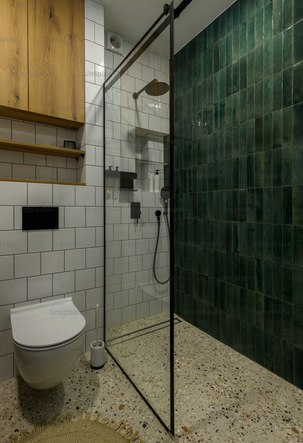 Modern bathroom with white and green tiled walls, a walk-in shower with a black frame, and a wall-mounted toilet. Wooden shelves are on the left wall.