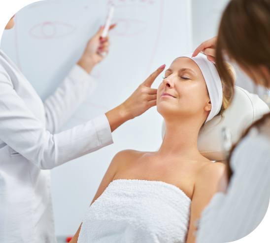 A woman receiving a facial treatment while lying with her eyes closed in a spa or clinic setting.