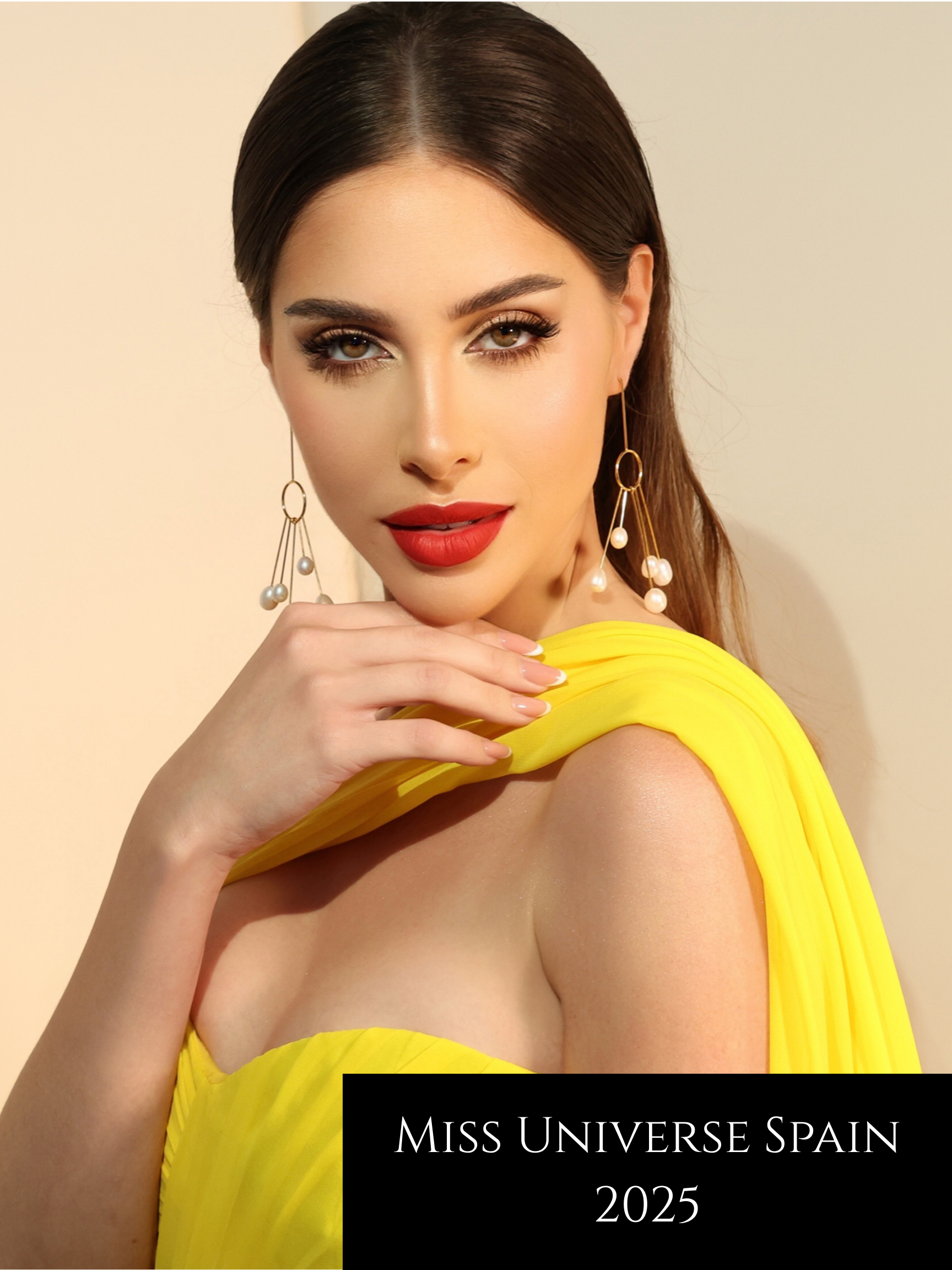 A woman in a yellow dress with red lipstick and dangling pearl earrings looks at the camera, with the text "Miss Universe Spain 2025" on the bottom right corner.