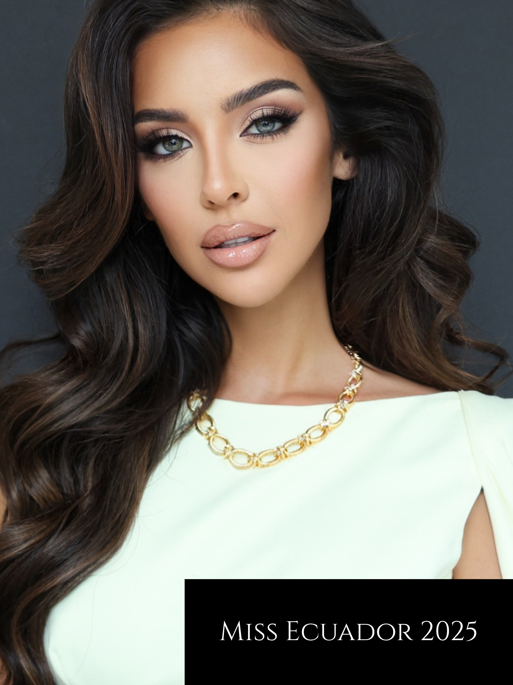 Close-up of a woman with long, wavy dark brown hair, blue eyes, makeup, and a gold necklace, wearing a light-colored top, with a black rectangle containing white text that reads 'Miss Ecuador 2025'.