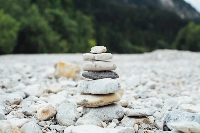 A stack of rounded stones stands steady on a riverbed, offering a simple moment of balance in nature.