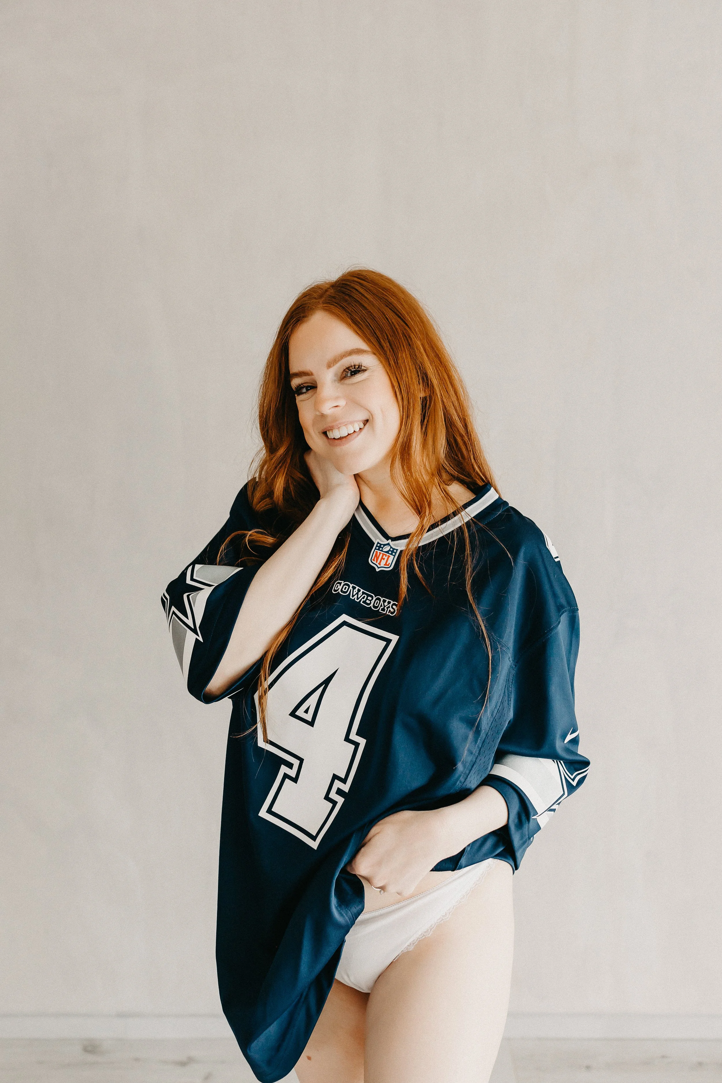 bride in white lace underwear and cowboys jersey smiling at the camera