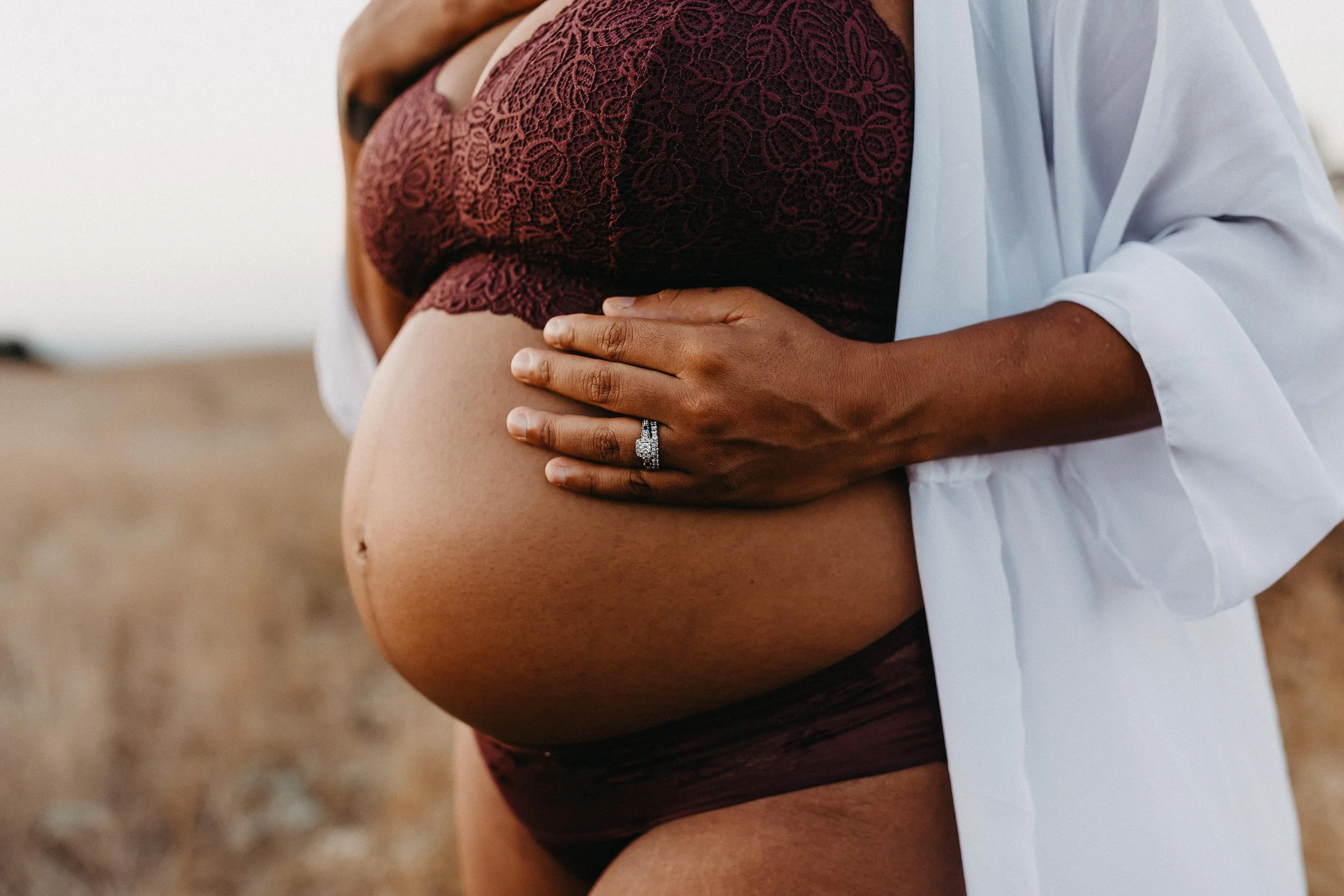 pregnant woman in matching maroon lace lingerie set with white robe