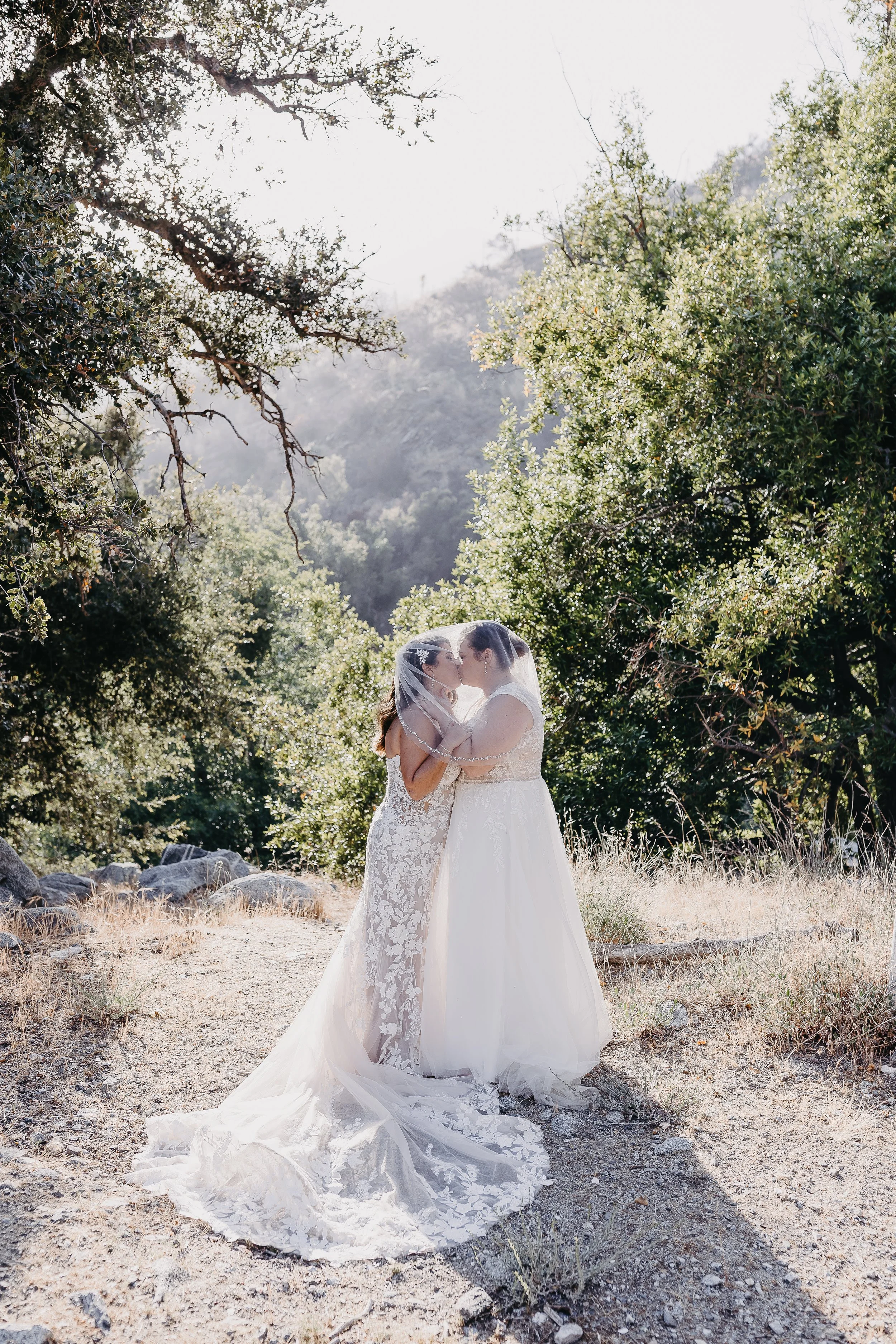 two brides kissing in their beautiful wedding gowns in Mount Baldy, California