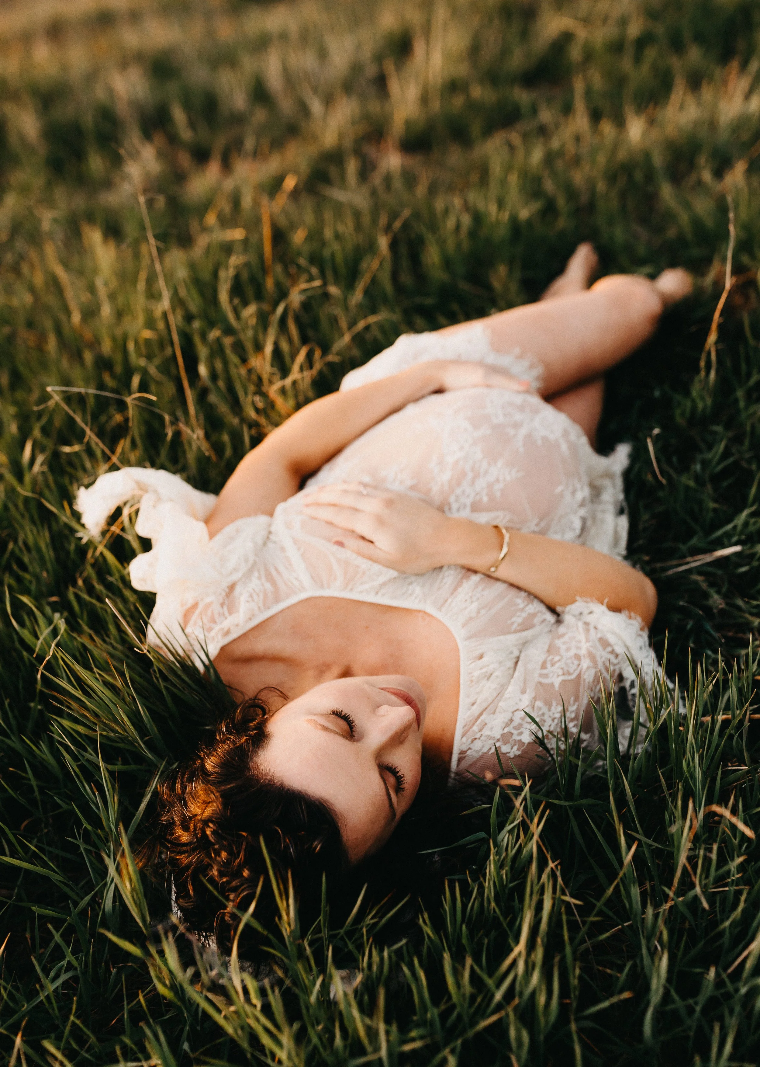 pregnant woman in see through lace chemise laying in tall grass