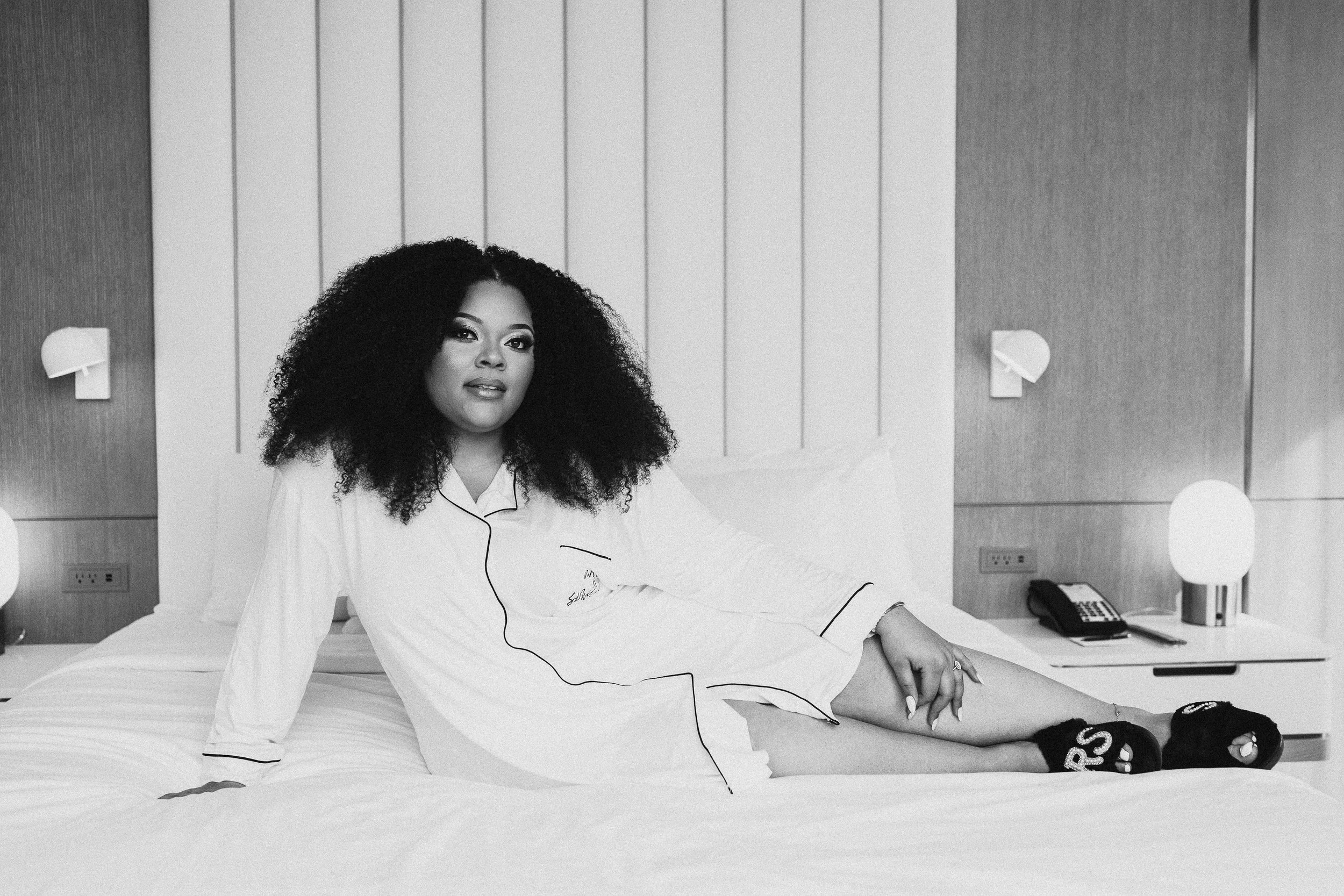 bride in button down matching pajamas laying posed on hotel bed