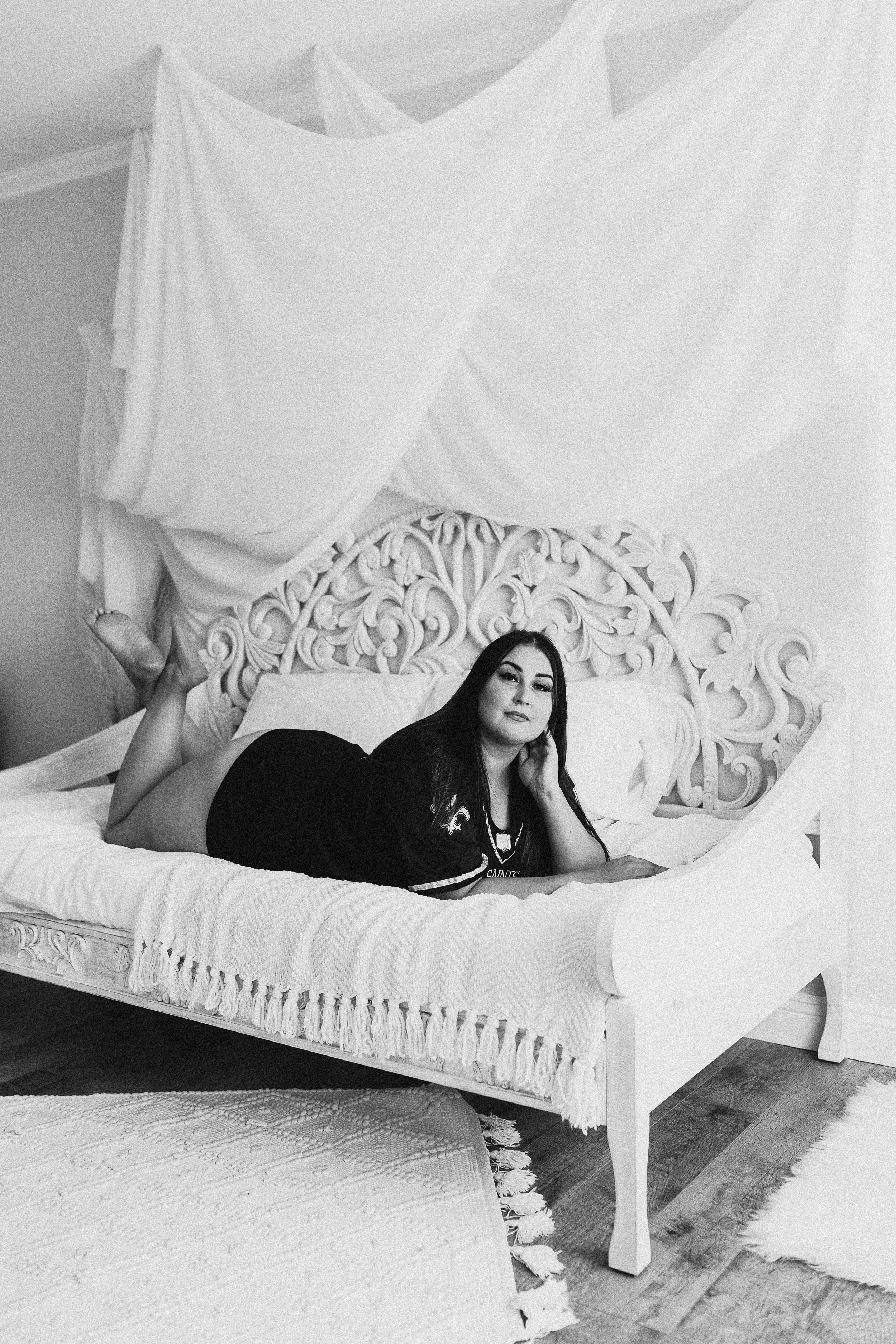 bride laying posed on all white bed in saints jersey