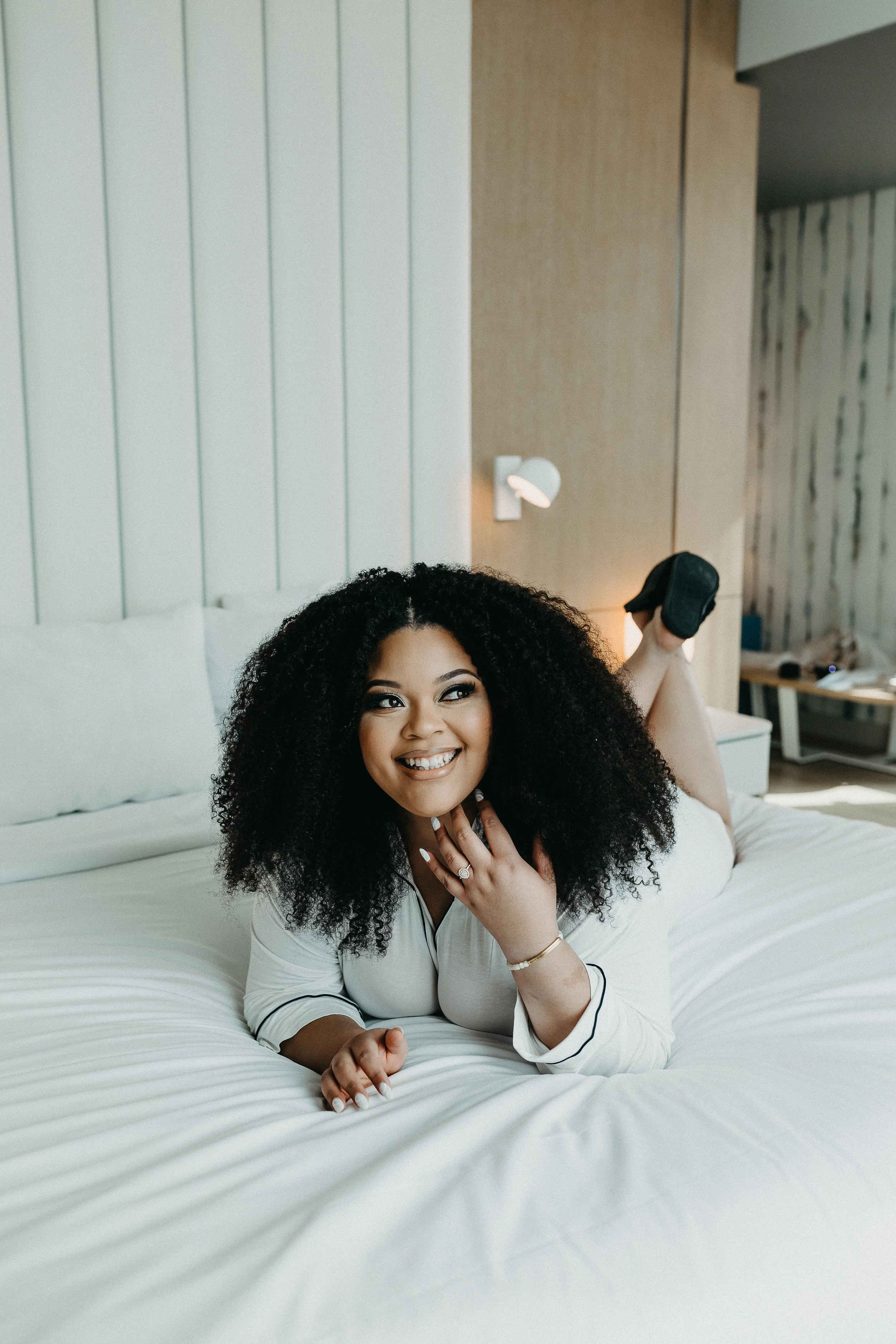 bride in matching pajamas laying on the hotel bed smiling