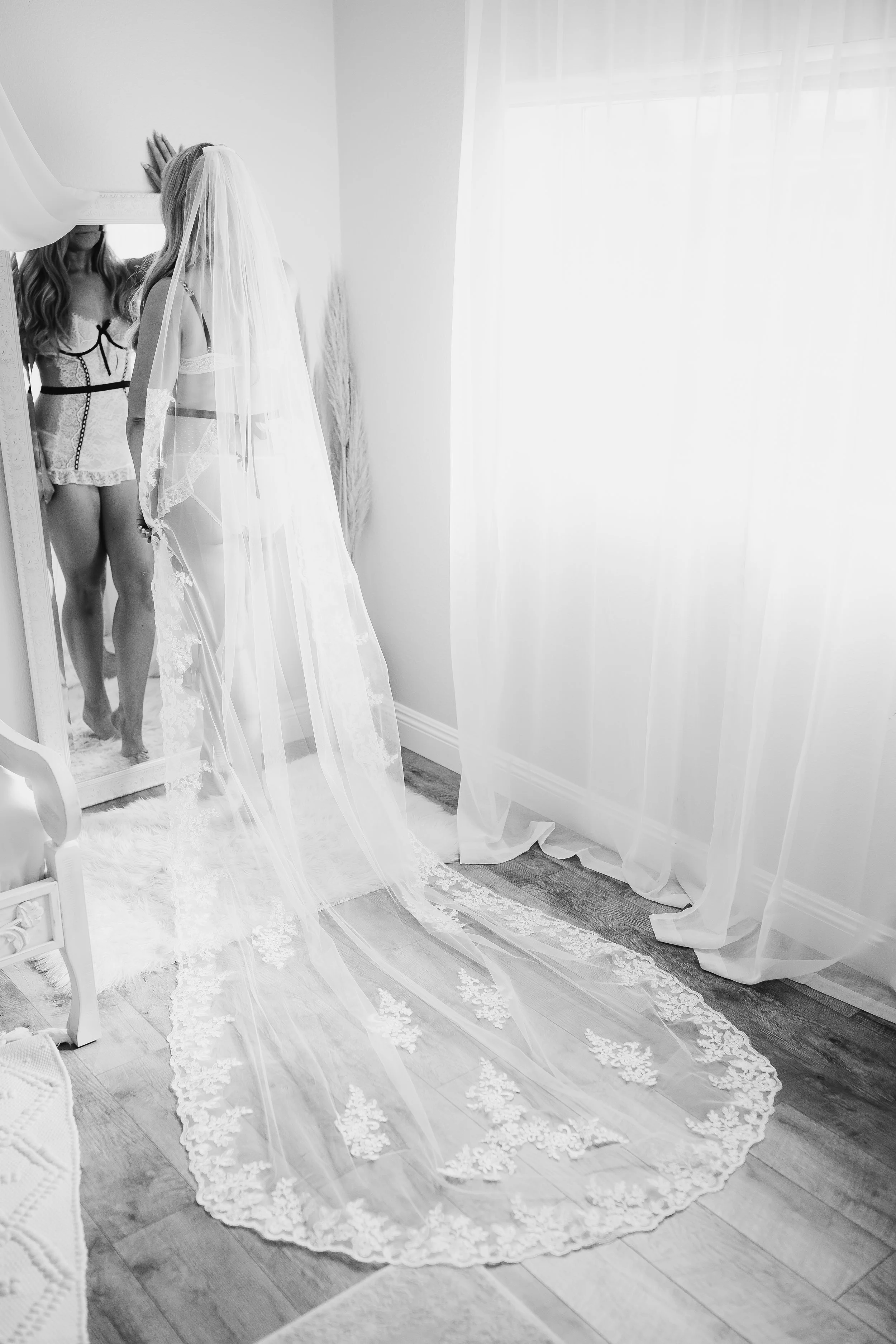 bride in front of full length mirror wearing matching lingerie set and cathedral lace veil