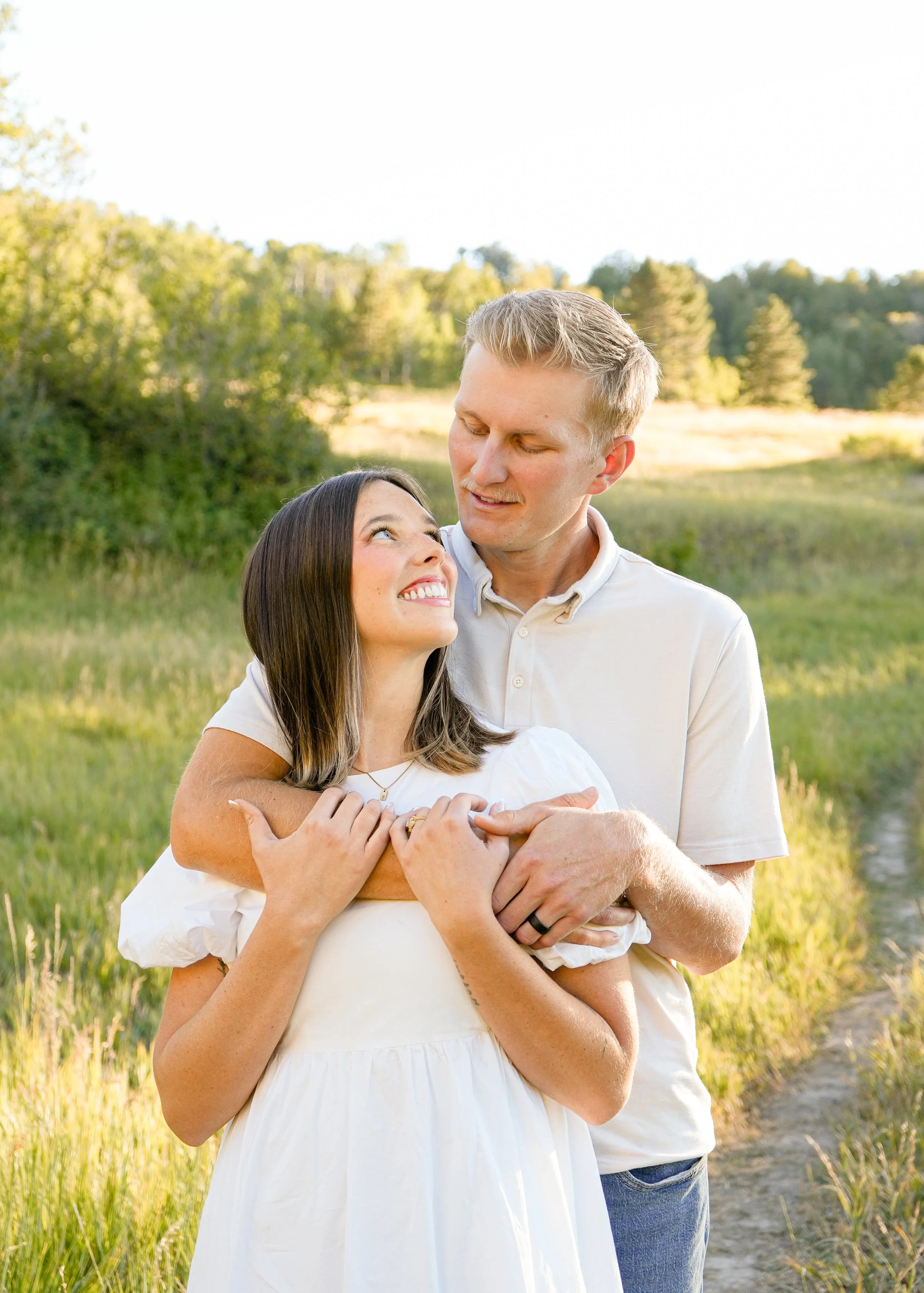 couple smiling at each other in a brightly-lit meadow