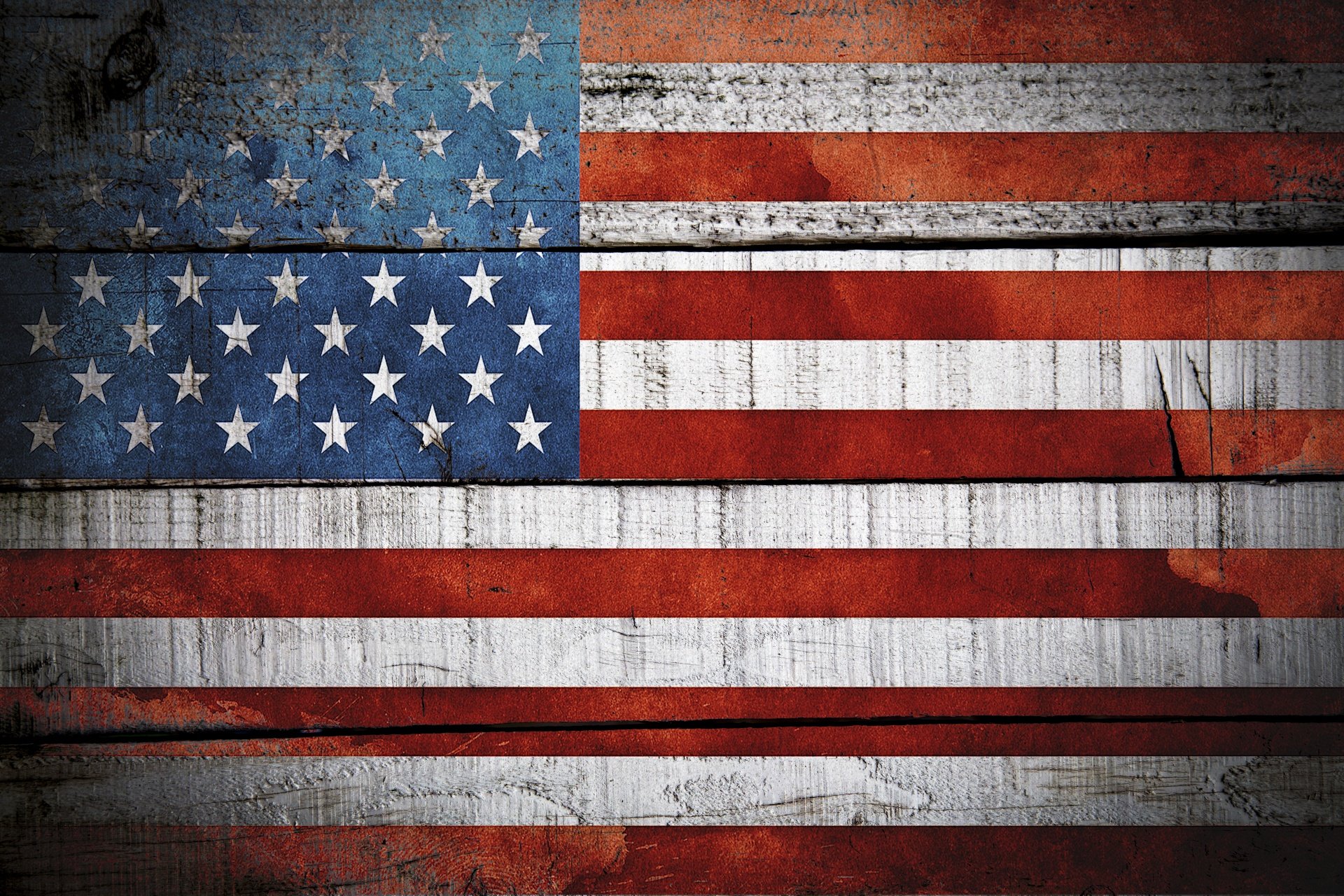 American flag painted on weathered wood with visible cracks and paint peeling.