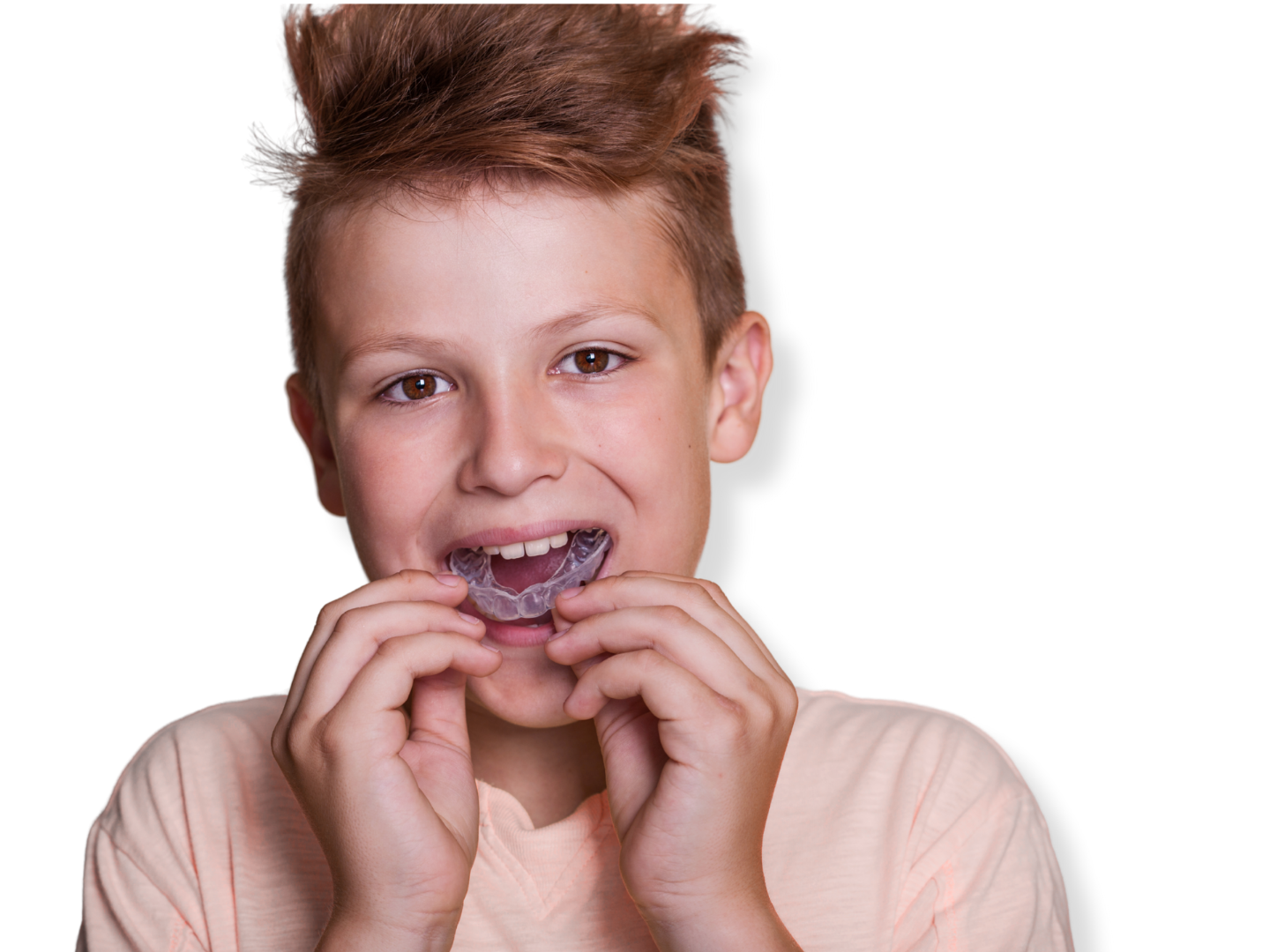 Boy with short, spiked reddish hair, smiling, holding a dental night guard near his mouth.